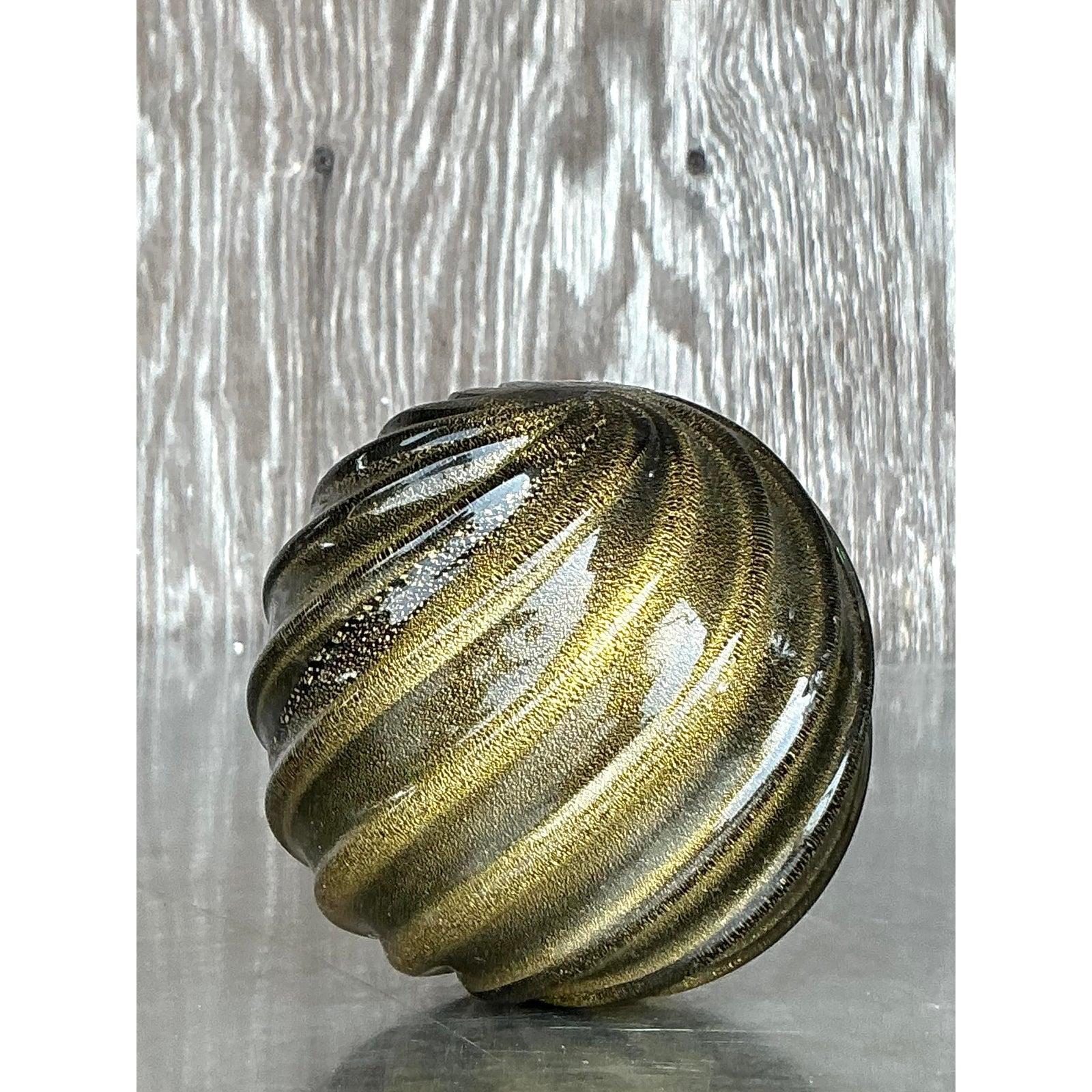 Porta il glamour e l'eleganza artigianale nel tuo spazio con questa splendida sfera in vetro soffiato vintage Regency. Con un'ampia gamma di sfumature d'oro metallico e di onice profondo, questa sfera scultorea emana un'opulenza senza tempo e un