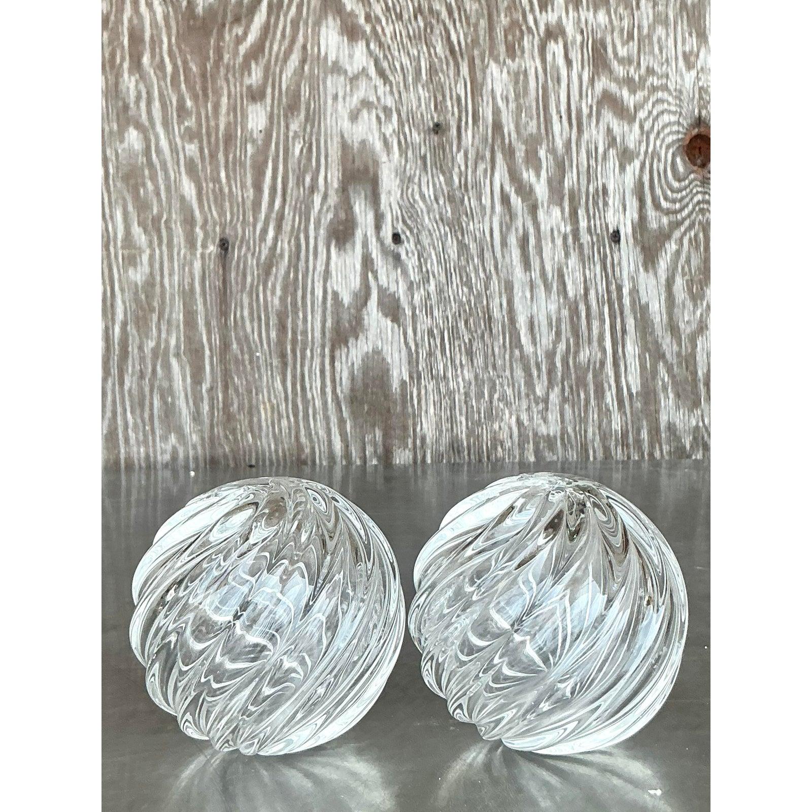 Cette exquise paire de sphères en verre soufflé de style Regency rehausse le style de votre intérieur. Fabriqué à la main avec un motif en spirale fascinant, chaque orbe rayonne de clarté, de symétrie et d'un sens sculptural du mouvement. Ces