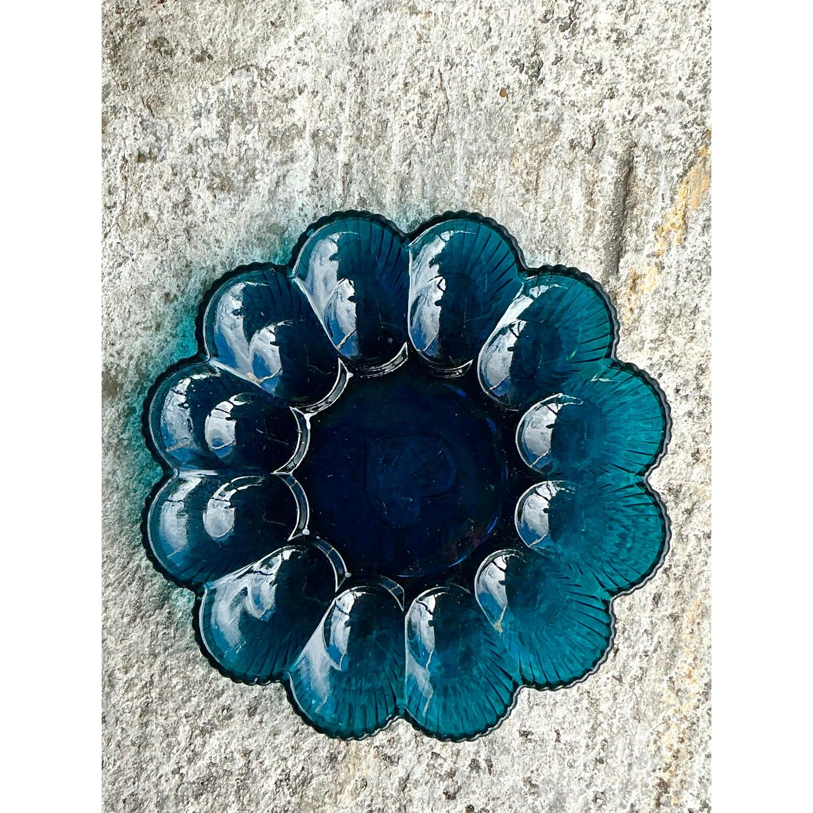 Serve with style and sparkle using this vintage blue glass deviled egg tray, a statement piece that blends function and elegance. Featuring a radiant scalloped design with twelve egg-shaped sections and a central well, this tray dazzles in rich
