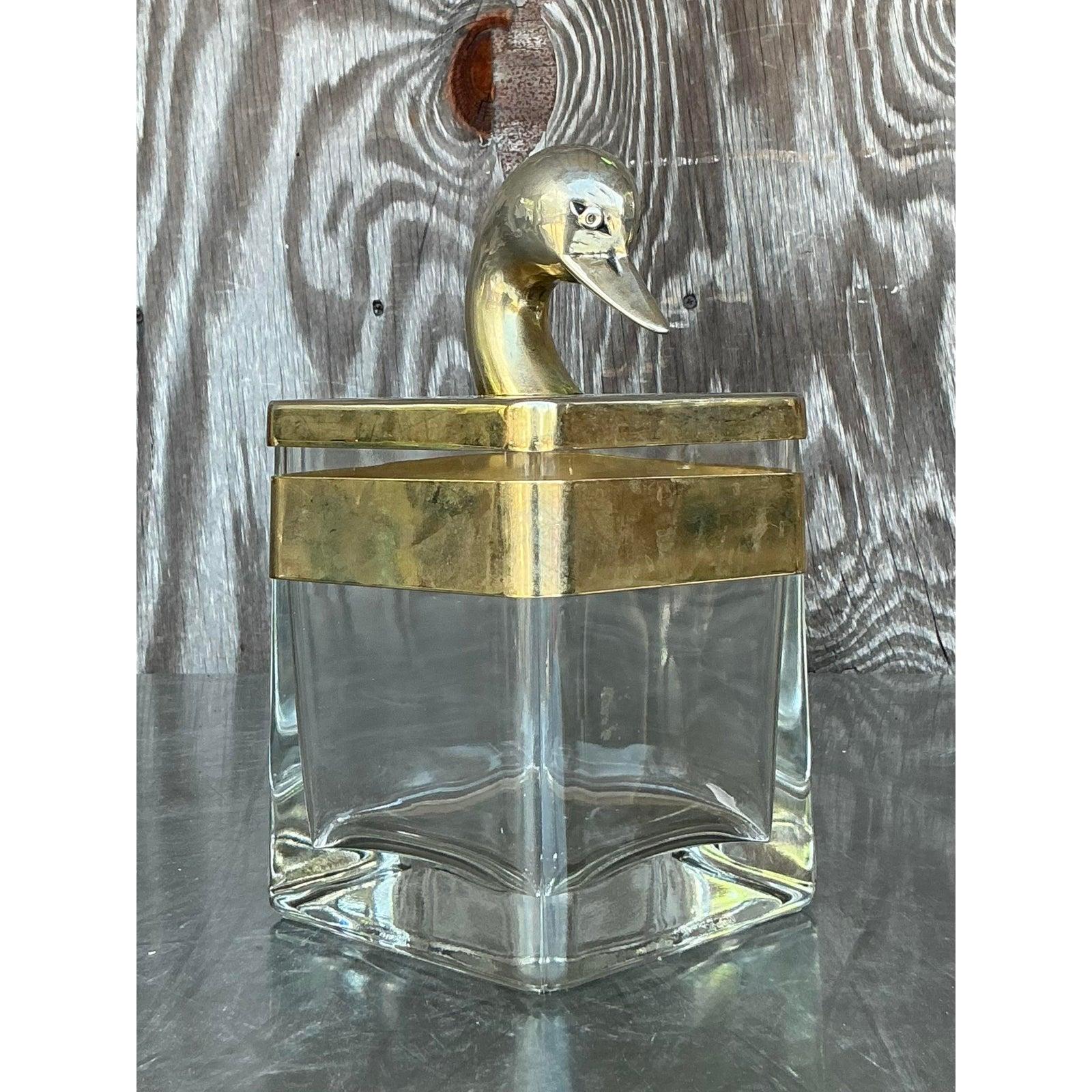 Eleva i tuoi interni con questo squisito contenitore vintage Regency in ottone e vetro, testimonianza di un'eleganza senza tempo e di un design sofisticato. Questo pezzo accattivante presenta un elegante corpo in vetro trasparente meticolosamente