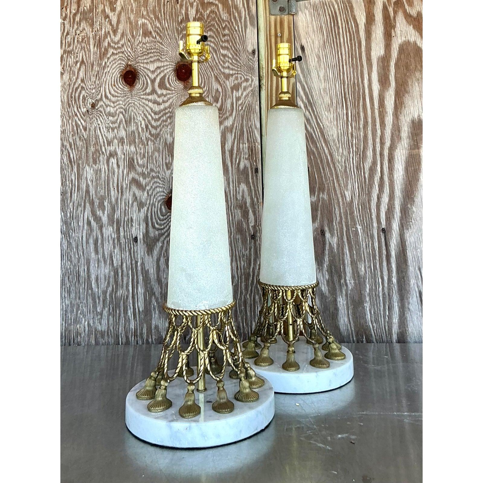 Exude pure Hollywood Regency glamour with this exquisite pair of vintage table lamps. Each lamp is a masterpiece of opulent design, featuring an intricate brass gallery of draped, twisted rope swags and a full fringe of charming tassels. This ornate