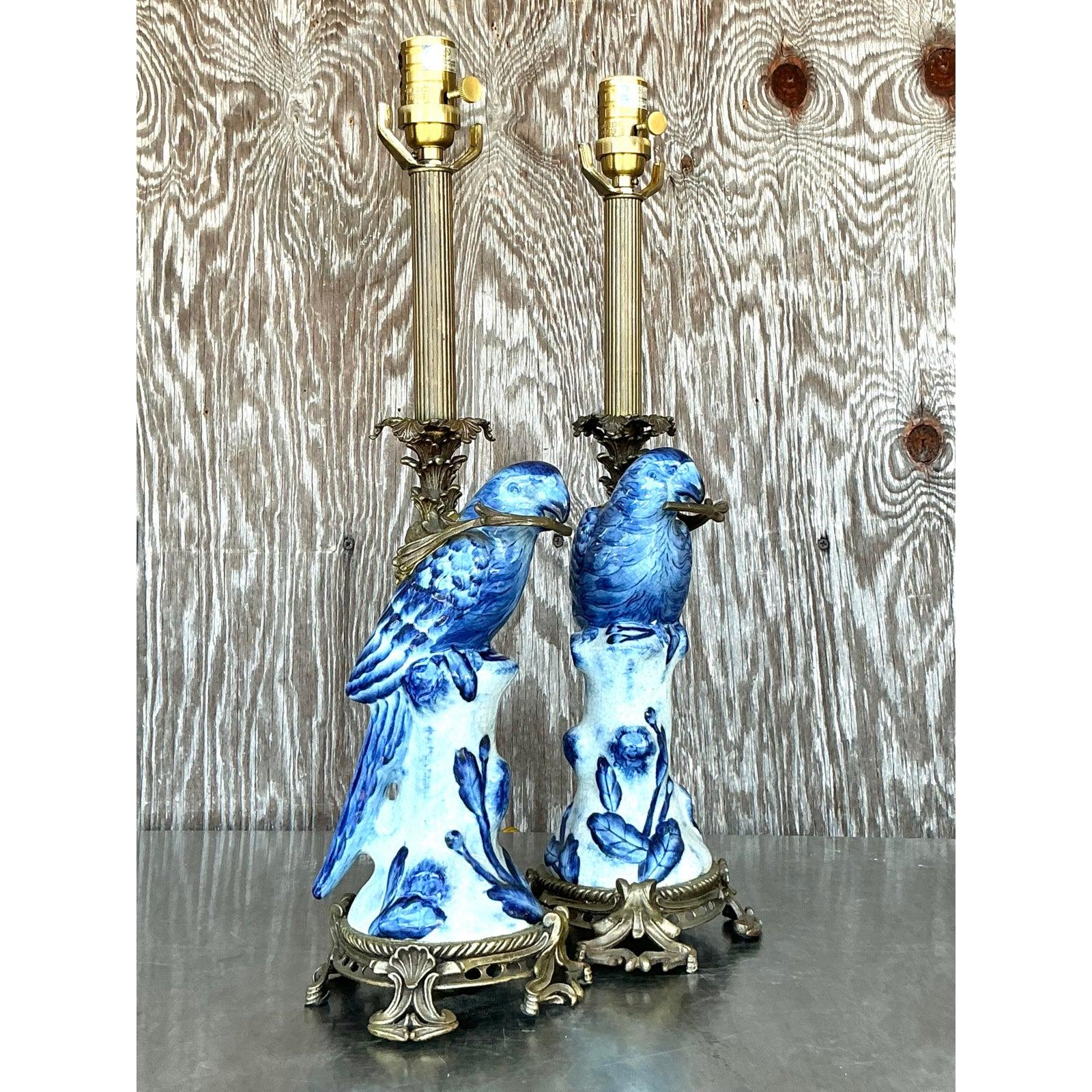 Eleva tu interior con este exquisito par de lámparas de pájaro envueltas en latón Vintage Regency, una encantadora fusión de ornamentada artesanía y elegancia aviar. Cada lámpara presenta un pájaro de cerámica azul y blanca bellamente esculpido