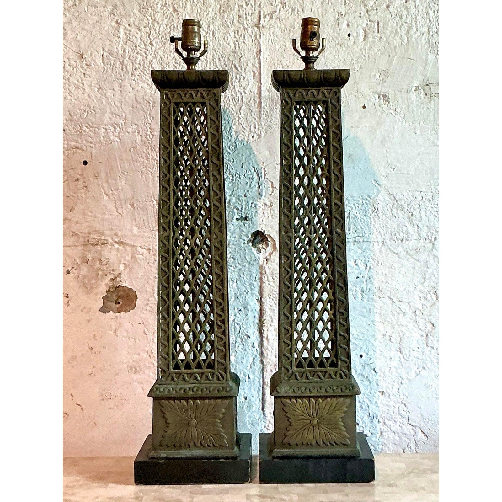 Ancla tu decoración con la grandeza arquitectónica de este magnífico par de lámparas vintage de estilo neoclásico. Con una majestuosa forma columnar, cada lámpara presenta un intrincado trabajo metálico de trefilado abierto acabado en un profundo