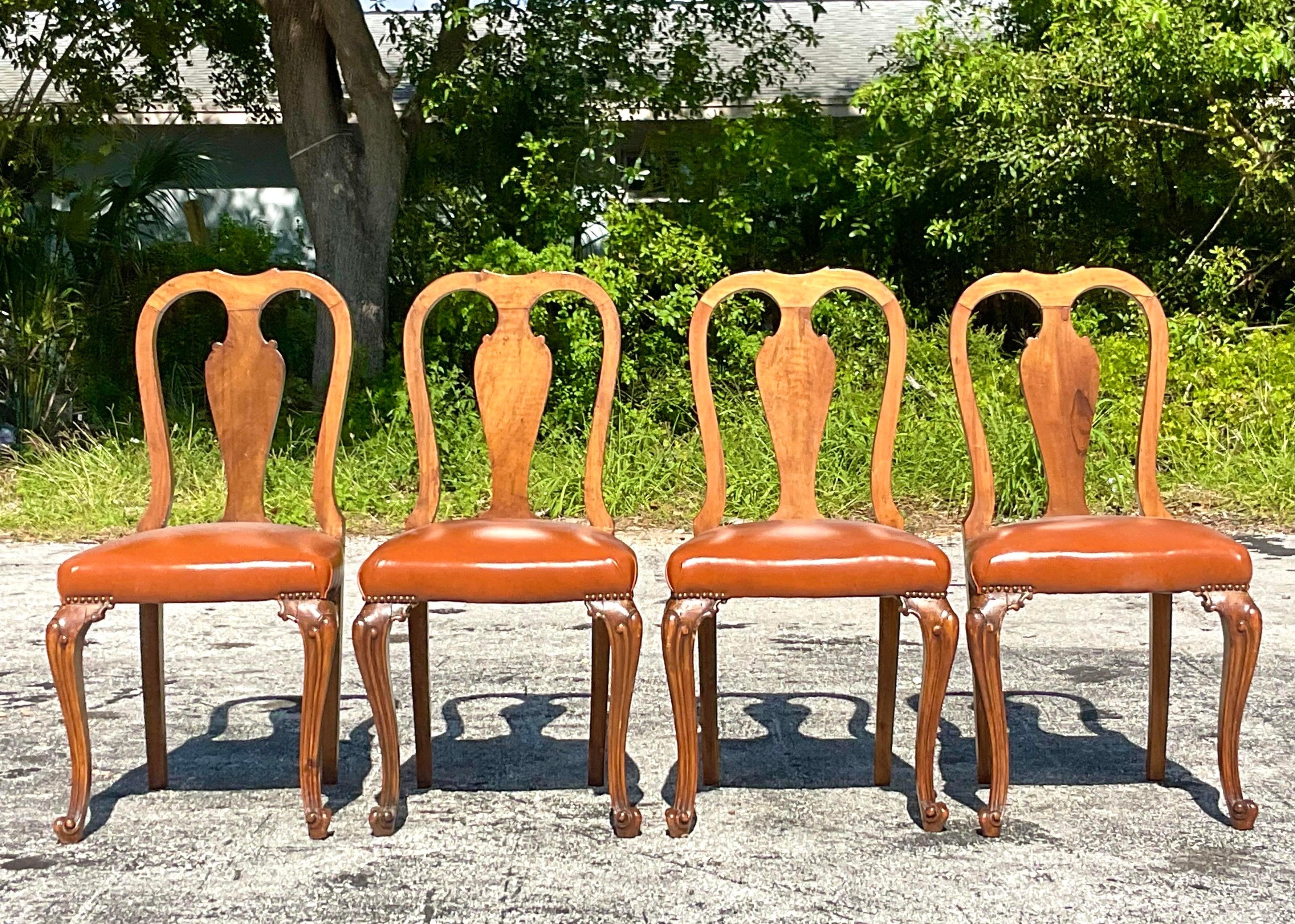 A magnificent set of four vintage Regency dining chairs. Chic high back burl wood design with carved cabriolet legs. Newly reupholstered with a caramel leather seat. Acquired from a Palm Beach estate.