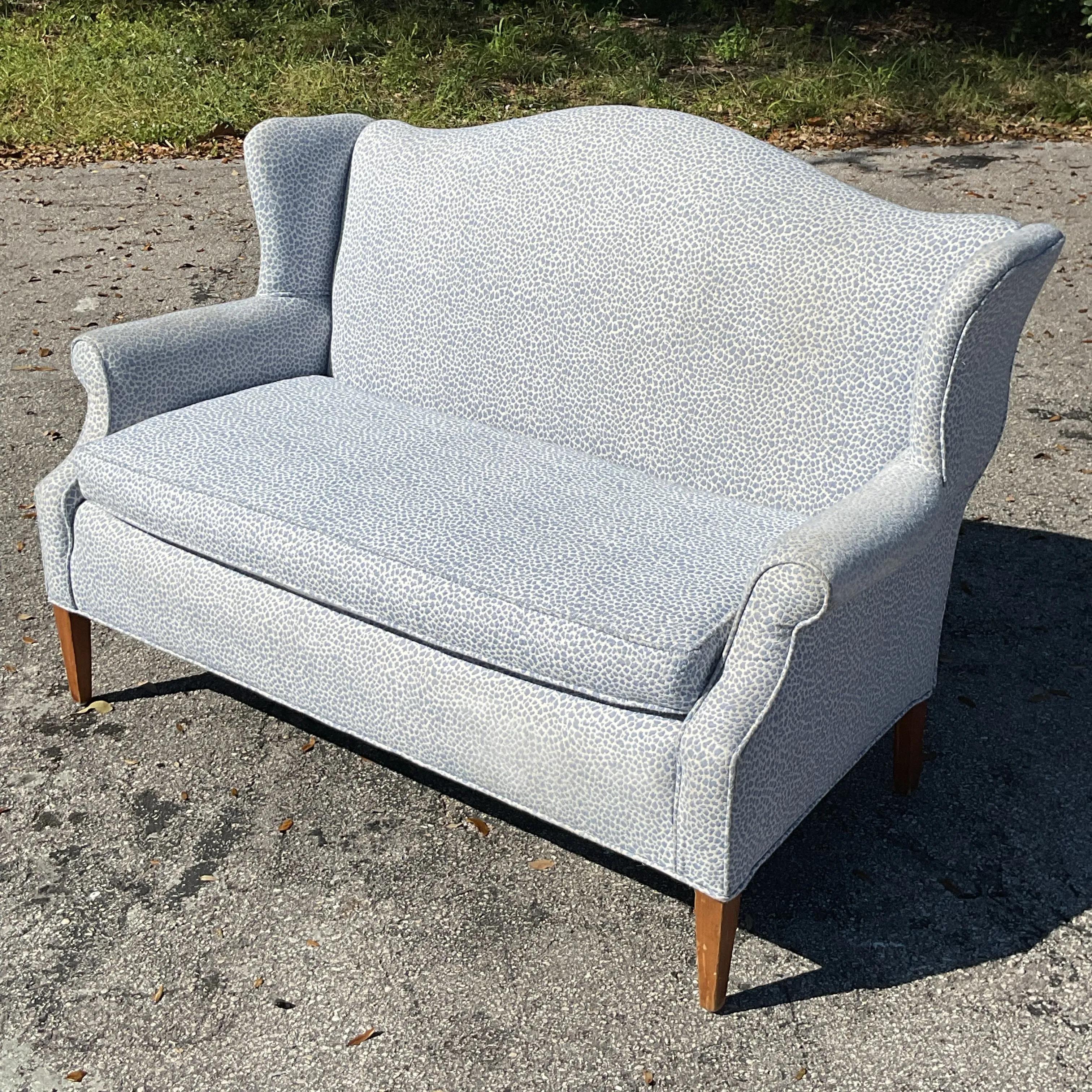A sophisticated Vintage Regency camelback loveseat showcasing a gracefully arched silhouette, plush upholstery, and elegant details. This timeless piece brings refined charm and comfortable seating to any living room, study, or sitting area.