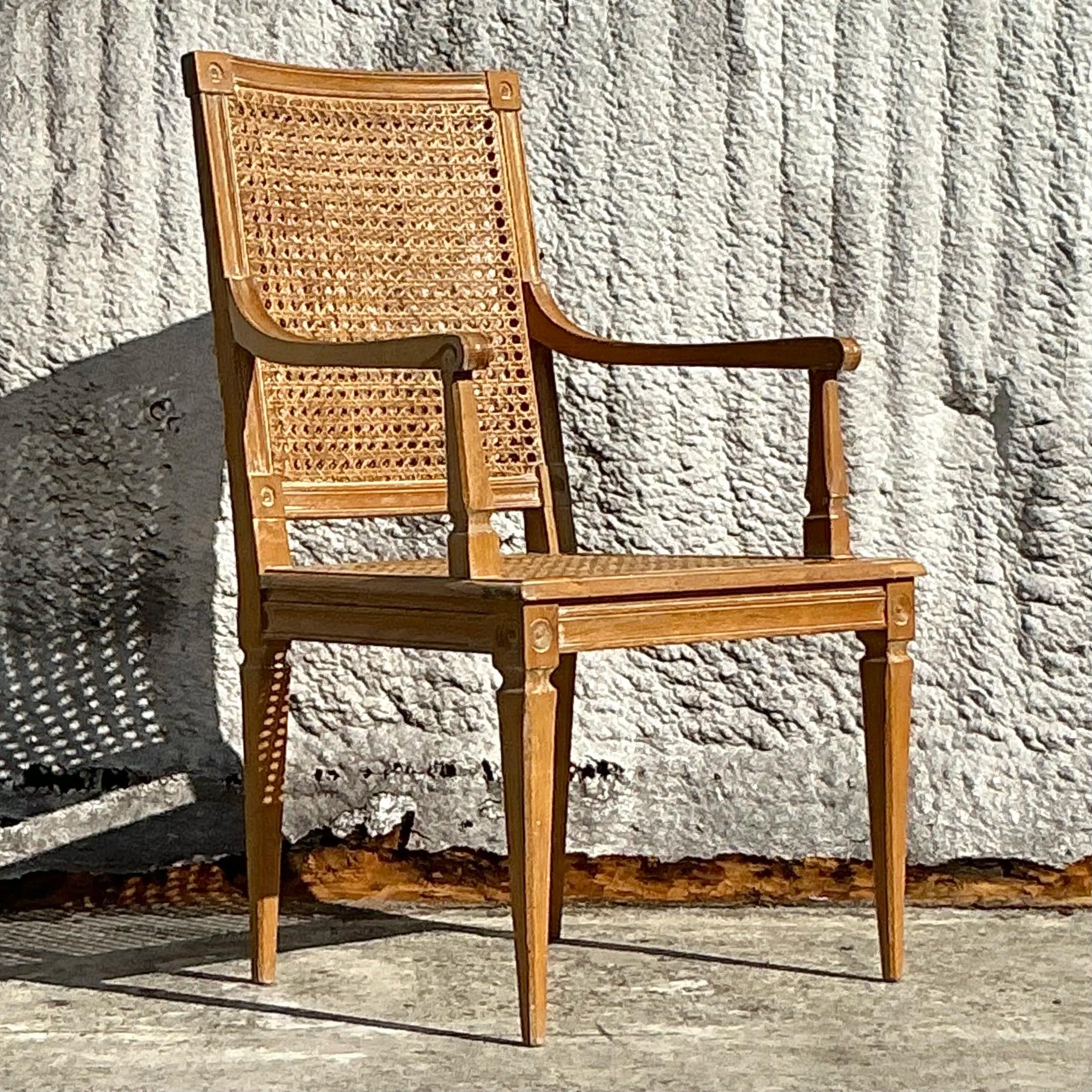 A timeless vintage Regency armchair featuring an elegant blend of cane and wood craftsmanship. The chair boasts a gracefully carved frame, a cane backrest, and a generously sized seat, offering both style and comfort. Perfect for adding a touch of