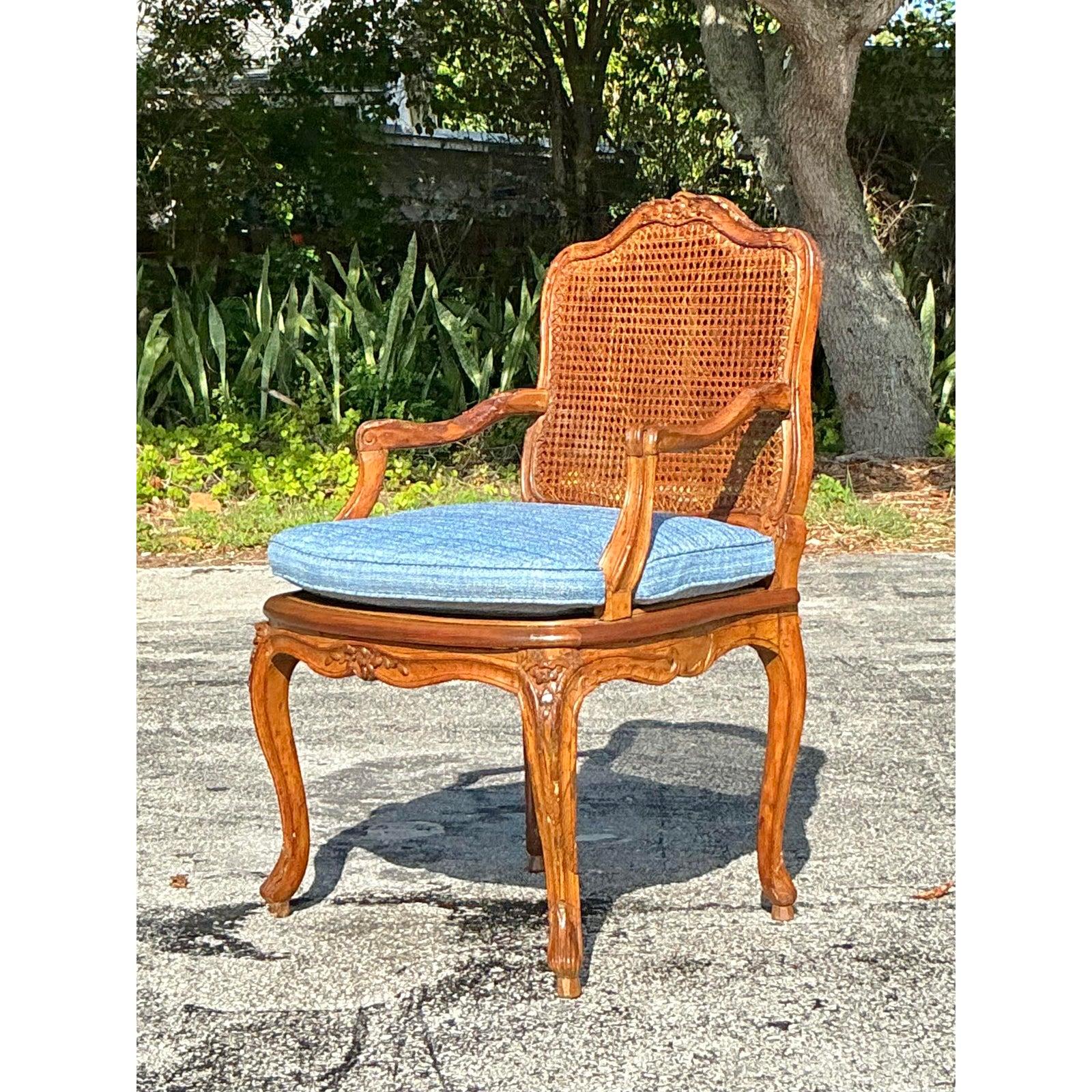 Eleva il tuo spazio con il fascino senza tempo di questa sedia vintage Regency Cane Fauteuil. La sedia presenta una struttura in legno intagliato con graziose gambe cabriole, un delicato motivo floreale e una silhouette elegantemente curvata. Lo
