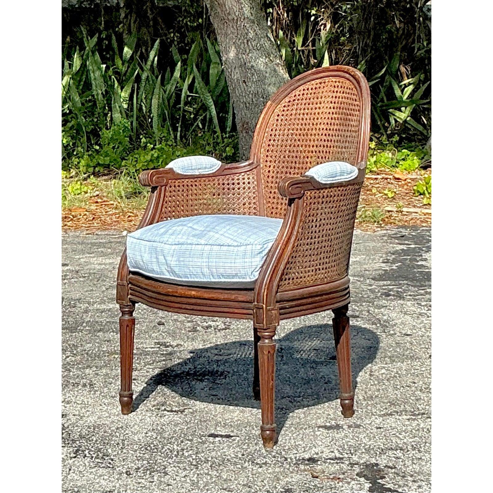 Verleihen Sie Ihrem Interieur einen Hauch zeitloser Eleganz mit diesem exquisiten Vintage Regency Bergère Chair. Mit seinem handgeschnitzten Holzrahmen mit anmutigen Kurven und raffinierten kannelierten Beinen ist dieses Stück ein wahres Zeugnis des