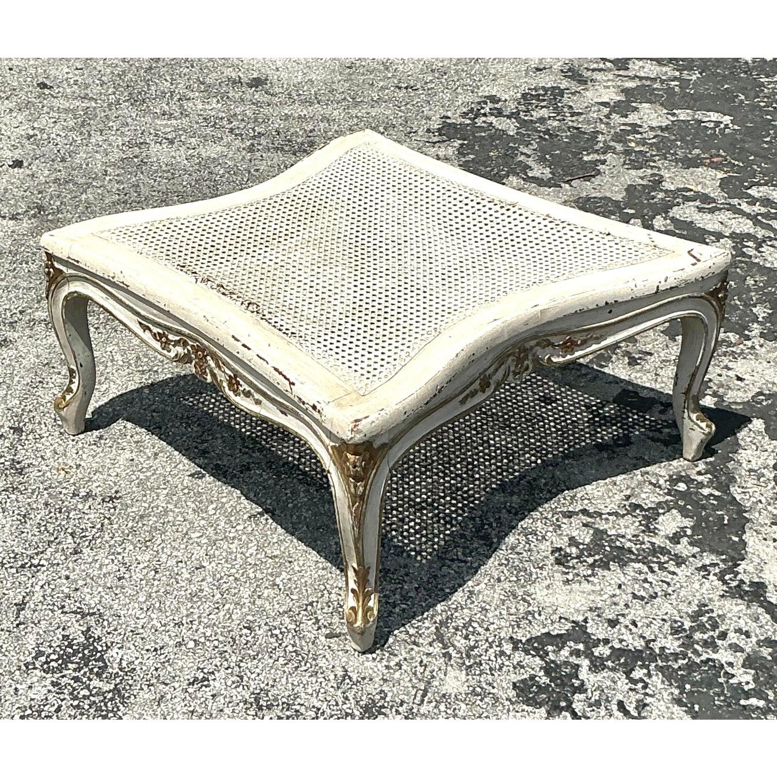 Infusez une élégance intemporelle à votre intérieur en utilisant ce pouf en rotin vintage Regency. Whiting est un cadre en bois sculpté et orné d'une finition blanche et or joliment vieillie. Cette pièce présente de délicates volutes rococo et des