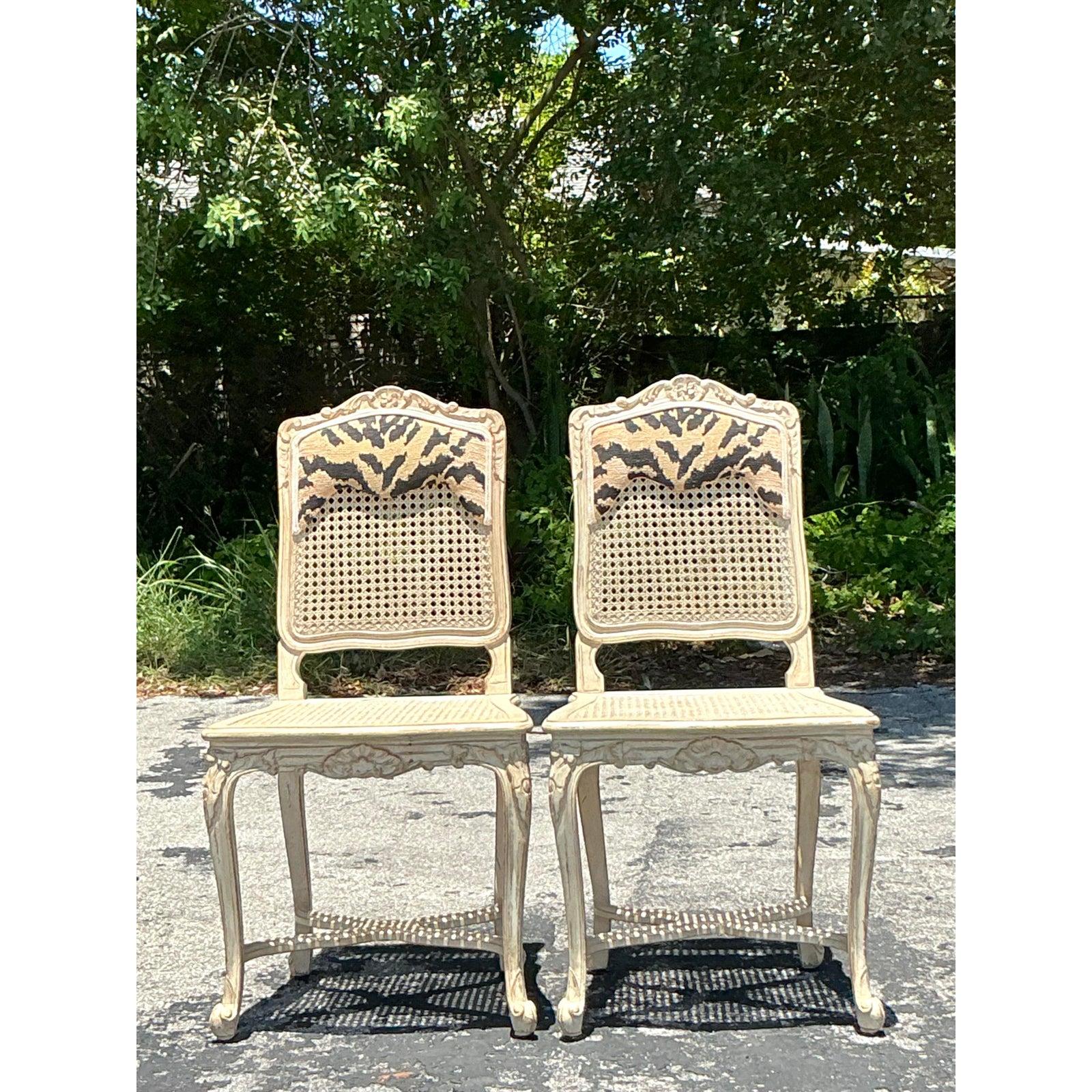 Step into an era of graceful sophistication with this captivating pair of Vintage Regency Cane Side Chairs. These exquisite chairs embody the delicate charm of French-inspired design, featuring beautifully carved wood frames finished in a lovely