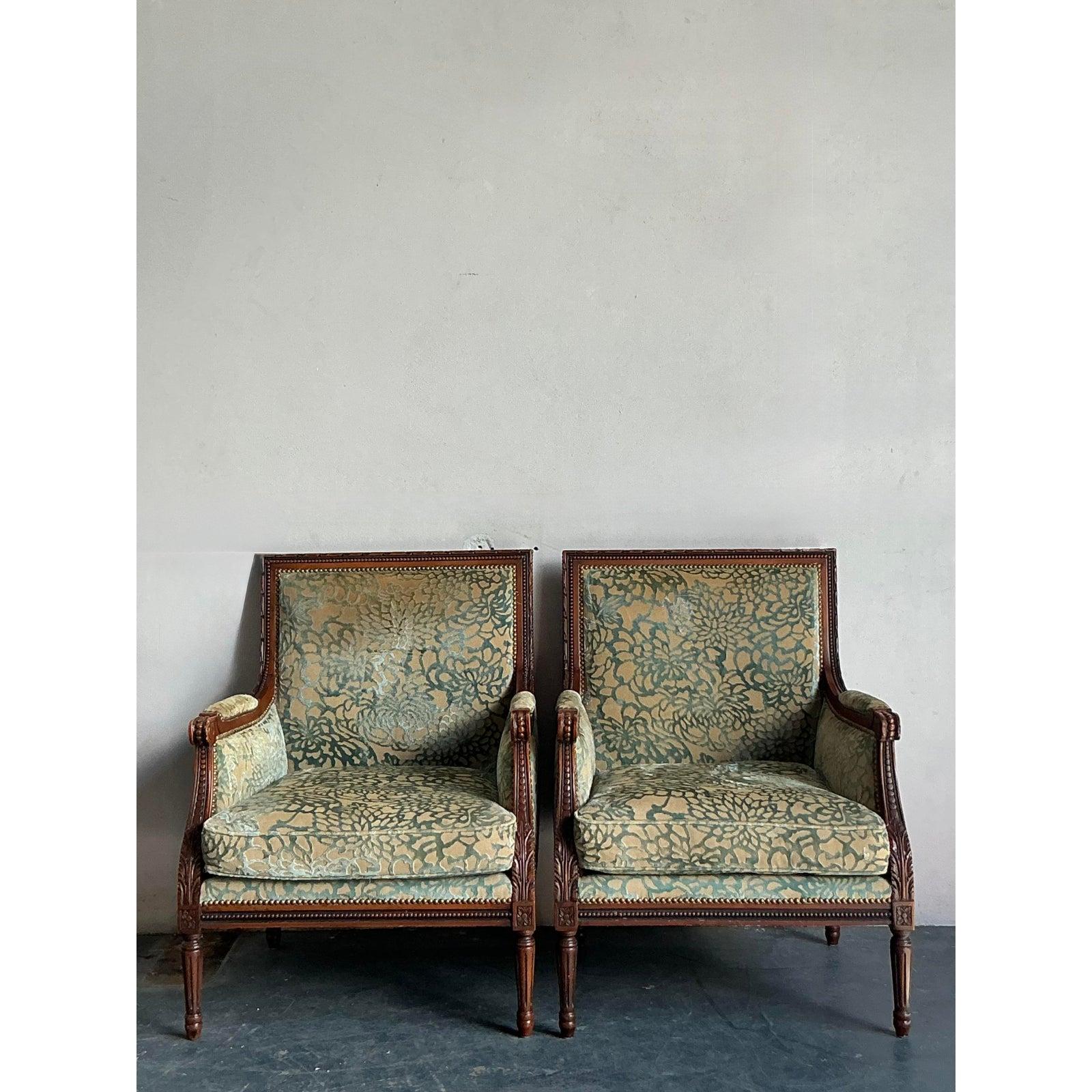Ti presentiamo una squisita coppia di sedie Bergere d'epoca, che incarnano l'eleganza sofisticata e l'intricata lavorazione artigianale caratteristica dell'epoca Hollywood Regency. Ogni sedia presenta una struttura in legno graziosamente intagliata,