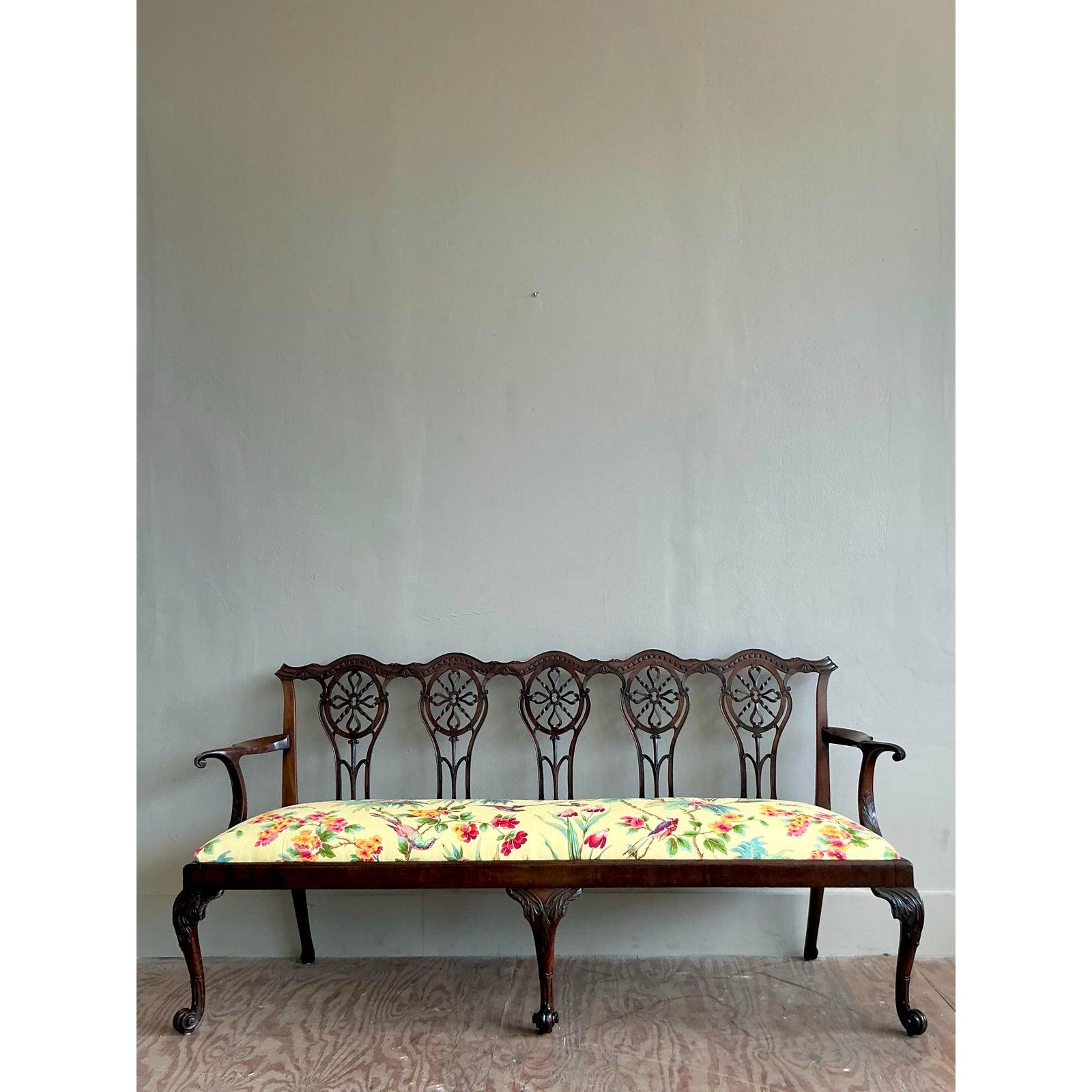 A remarkable example of timeless Georgian design, this vintage carved bench is a masterclass in sophisticated craftsmanship. The elegant mahogany frame showcases an incredible level of artistry, from its gracefully scrolled arms to the five