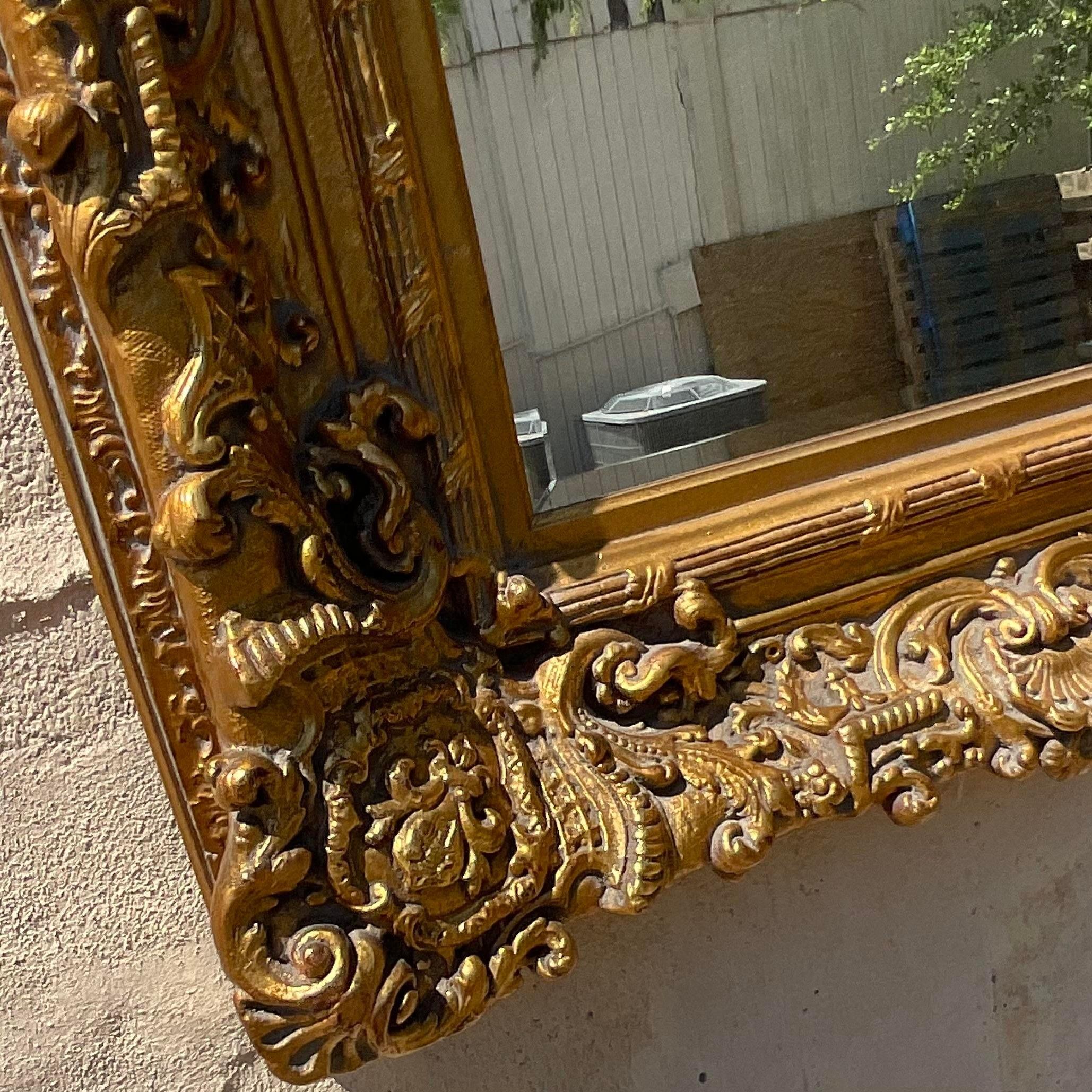 Indulge in timeless luxury with our Vintage Regency Carved Gilt Wood Mirror. American-crafted, this mirror showcases exquisite gilt wood carving, blending classic Regency elegance with artistic craftsmanship for a lavish and elegant addition to any