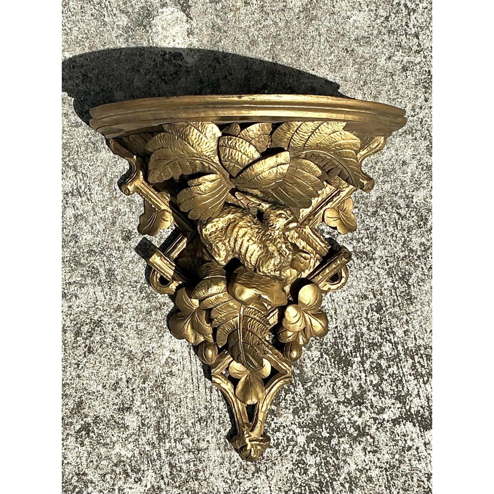 Heben Sie Ihre Wanddekoration mit dieser opulenten, geschnitzten und vergoldeten Vintage-Regency-Holzkonsole hervor, die klassische Raffinesse ausstrahlt. Dieses vergoldete Wandregal mit seinem exquisiten handgeschnitzten Design aus üppigem Laub,