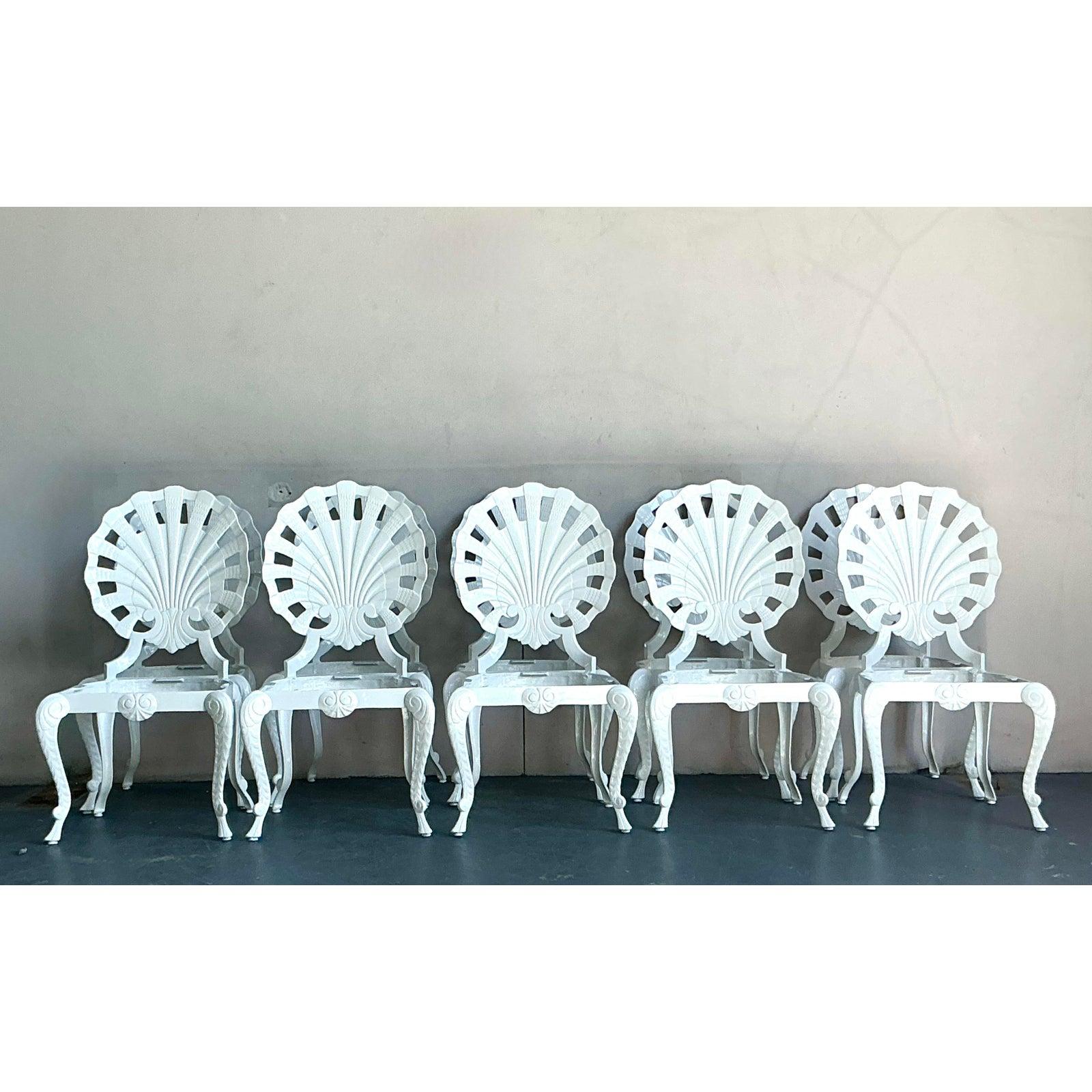 This exceptional set of ten vintage dining or garden chairs embodies the whimsical glamour of the Grotto and Hollywood Regency styles. Each chair is masterfully crafted from cast aluminum, featuring a striking seashell or scallop back design that