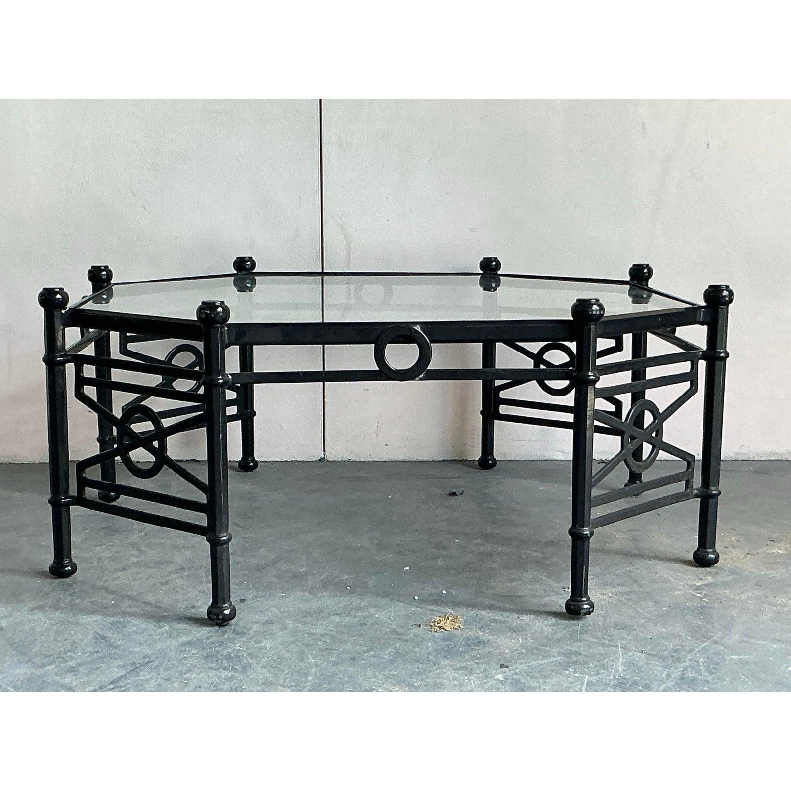 Anchor your living space with this striking vintage octagonal coffee table. A fantastic example of Hollywood Regency design, this table features a robust cast aluminum base finished in a sleek black, creating a bold, graphic silhouette. The frame is