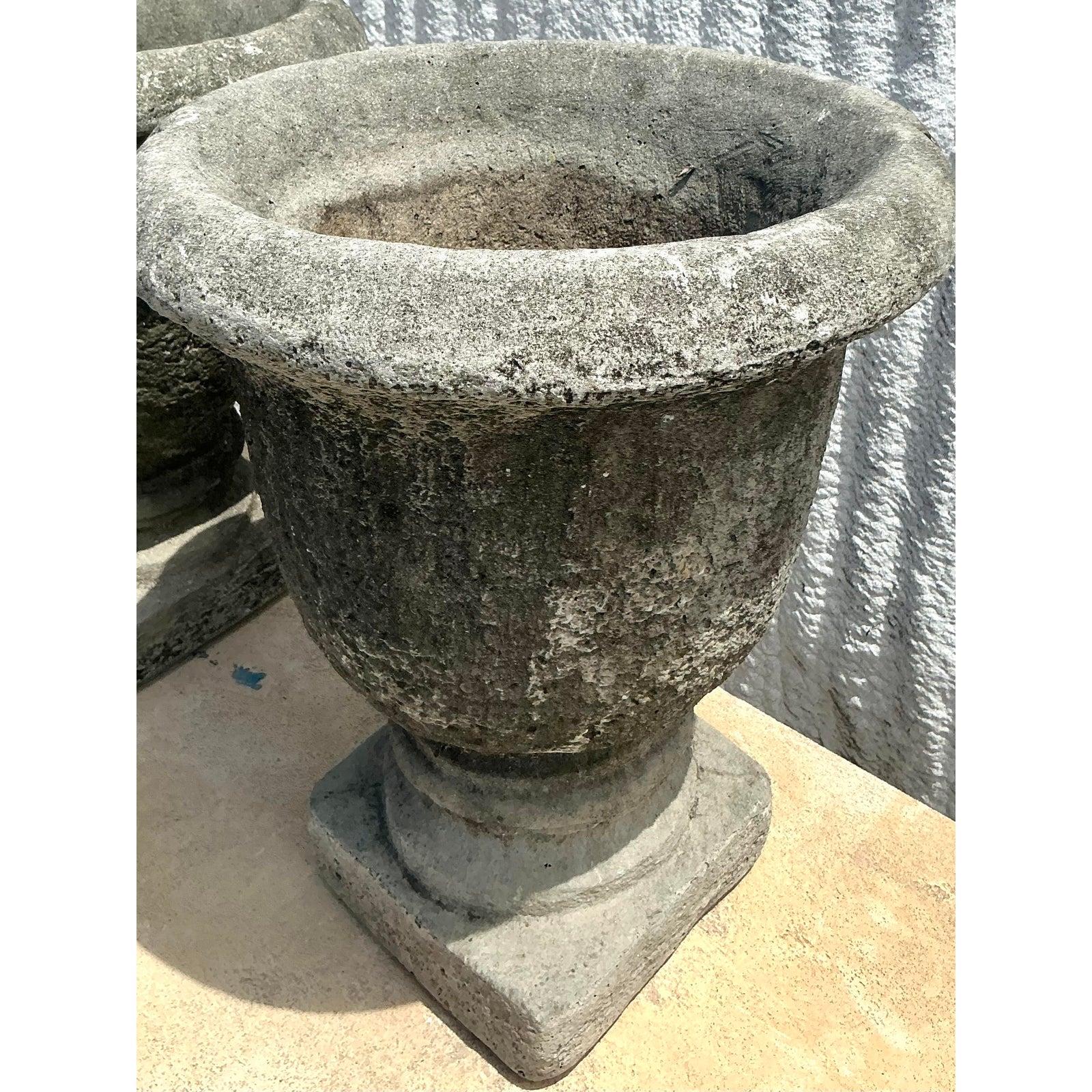 Timeless and classically elegant, this pair of Vintage Regency Cast Cement Planters adds refined grandeur to any garden, terrace, or entryway. With their fluted urn silhouette, rolled rims, and pedestal bases, these cast stone vessels are