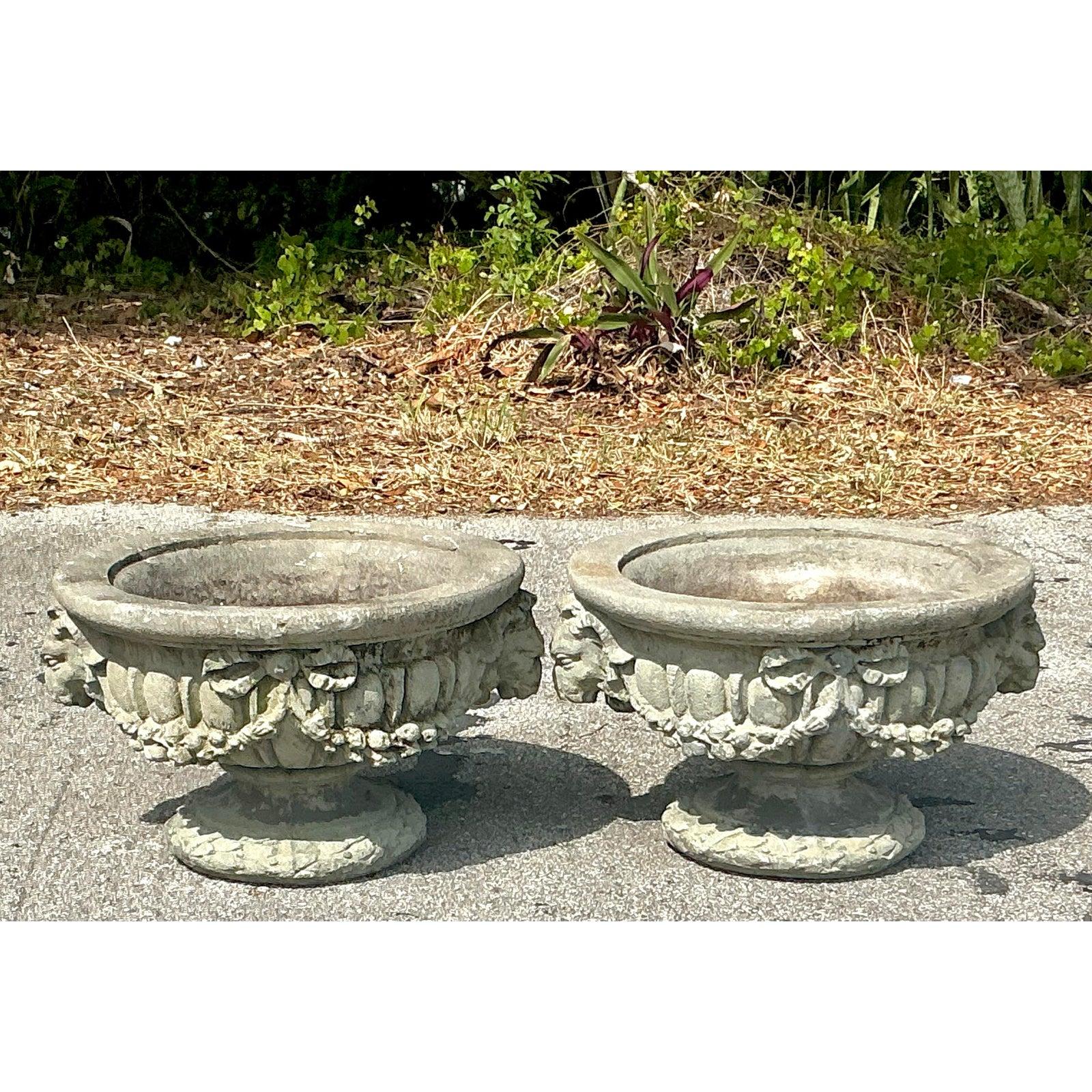 Aggiungi un tocco di grandezza neoclassica al tuo giardino, al tuo ingresso o al tuo patio con questa splendida coppia di urne d'epoca in calcestruzzo fuso, caratterizzate da regali accenti a testa di ariete e da dettagli ornamentali in rilievo.