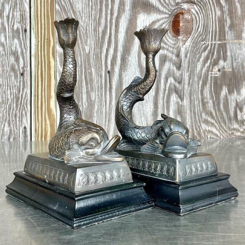 Illumina il tuo spazio con questa accattivante coppia di candelieri vintage Hollywood Regency a forma di delfino, che incarnano la grazia acquatica e il design opulento. Ogni candeliere presenta una figura di delfino finemente dettagliata, che si