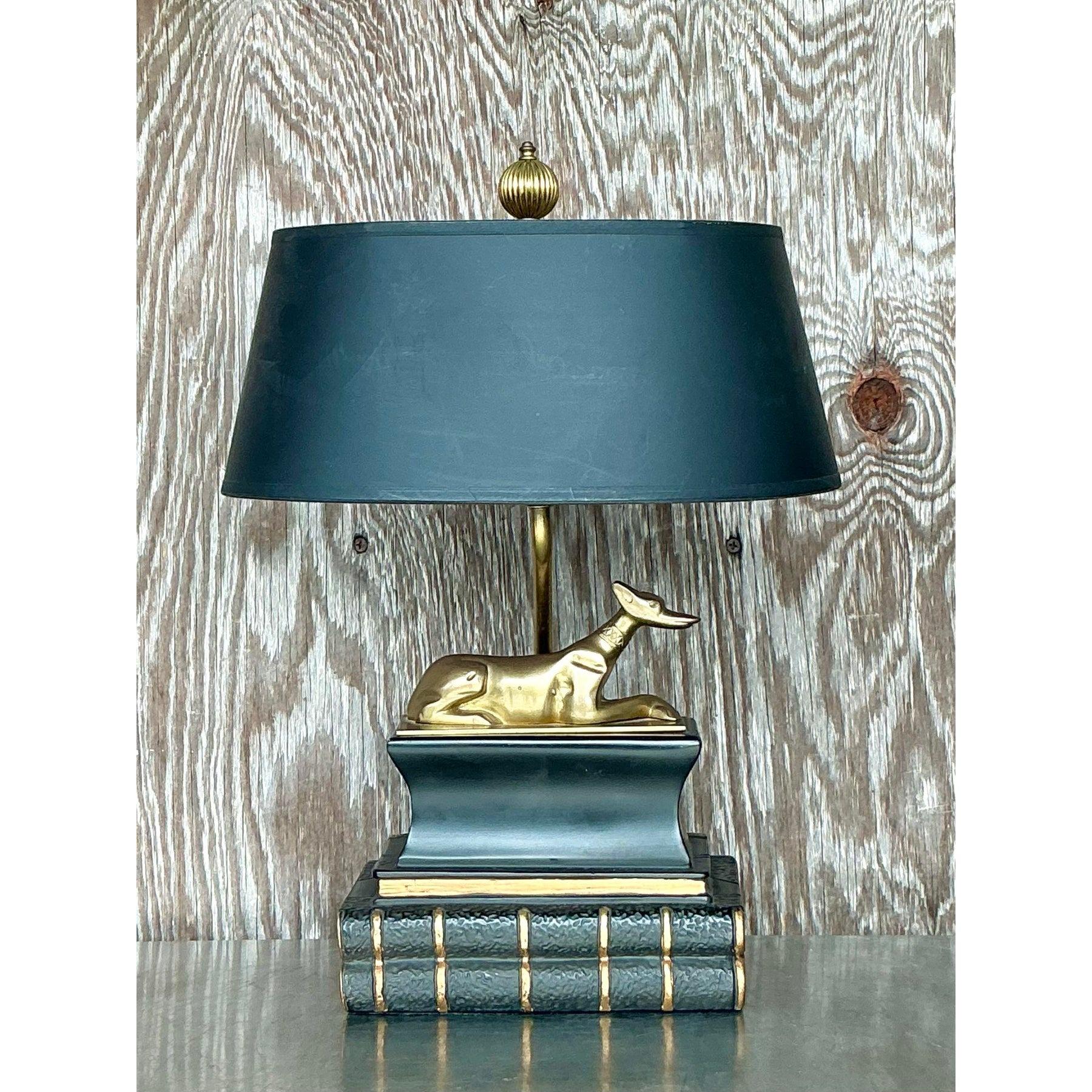 Questa splendida lampada vintage in stile Regency di Chapman presenta un'impressionante scultura di cane in ottone che poggia su una sofisticata base a libro impilata. L'elegante tonalità nera contrasta magnificamente con i dettagli dorati,