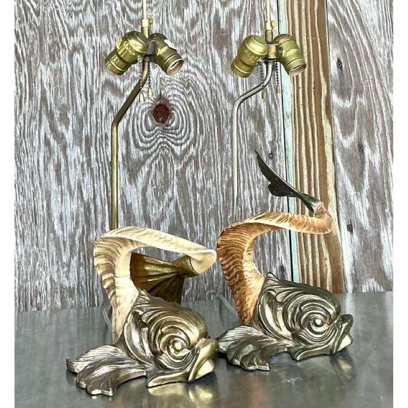 Make a stunning statement with this rare and documented pair of vintage table lamps by the renowned Chapman Manufacturing Company. Dated 1977, these lamps are a quintessential example of Hollywood Regency glamour, featuring sculptural koi fish bases