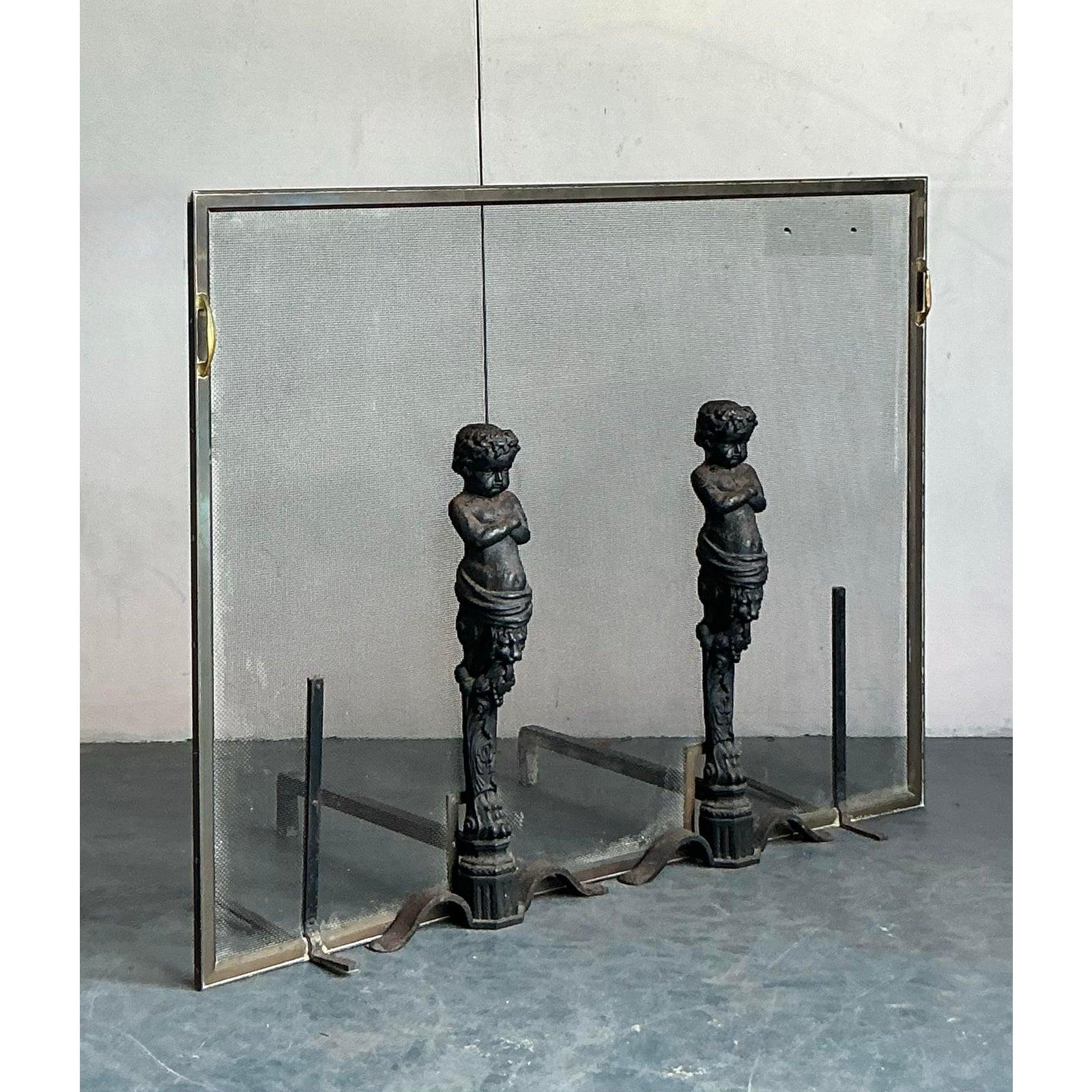 Anchor your hearth with the aristocratic charm of this vintage fireplace set. The design is masterfully centered on a pair of stunning figural andirons, crafted from heavy cast iron and featuring classical cherubs (or putti) standing atop ornate,
