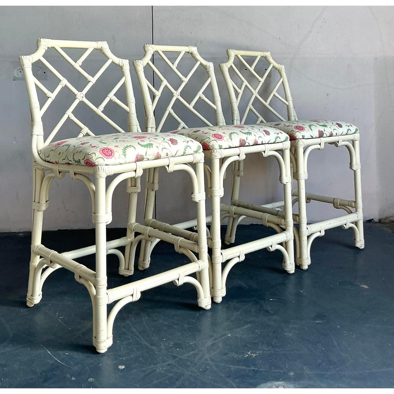 Channel the timeless glamour of Hollywood Regency with this stunning set of three Chinese Chippendale counter stools. The iconic fretwork backrests and faux bamboo frames, finished in a chic cream lacquer, evoke a sense of sophisticated, worldly