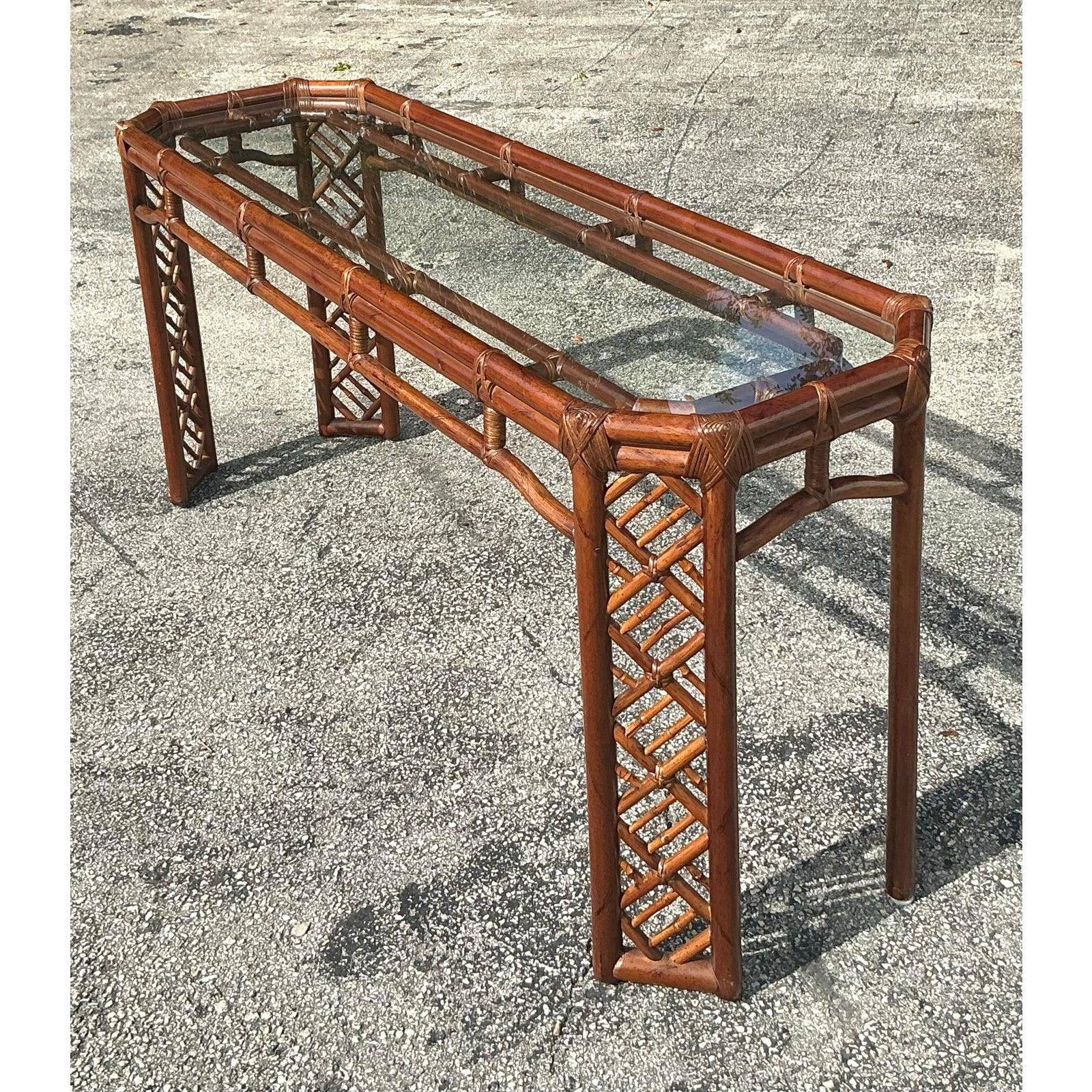 This vintage Regency Chinese Chippendale console table is a stunning blend of intricate craftsmanship and timeless design. Featuring an elegant bamboo and rattan frame with a signature latticework design, this table exudes classic sophistication.