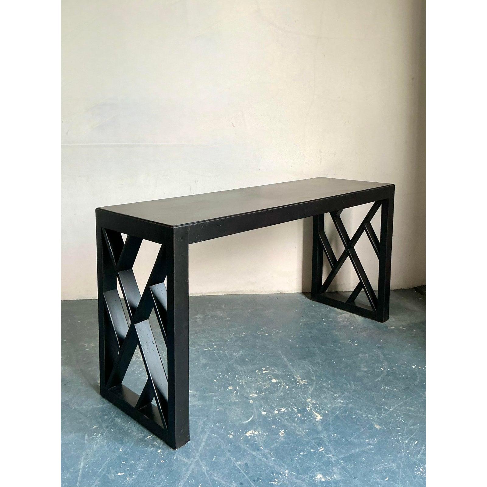 This sleek console table offers a sophisticated blend of minimalist geometry and bold modern structure. Finished in a rich, dark espresso or satin black hue, the table features a clean, substantial tabletop supported by an asymmetrical base: a
