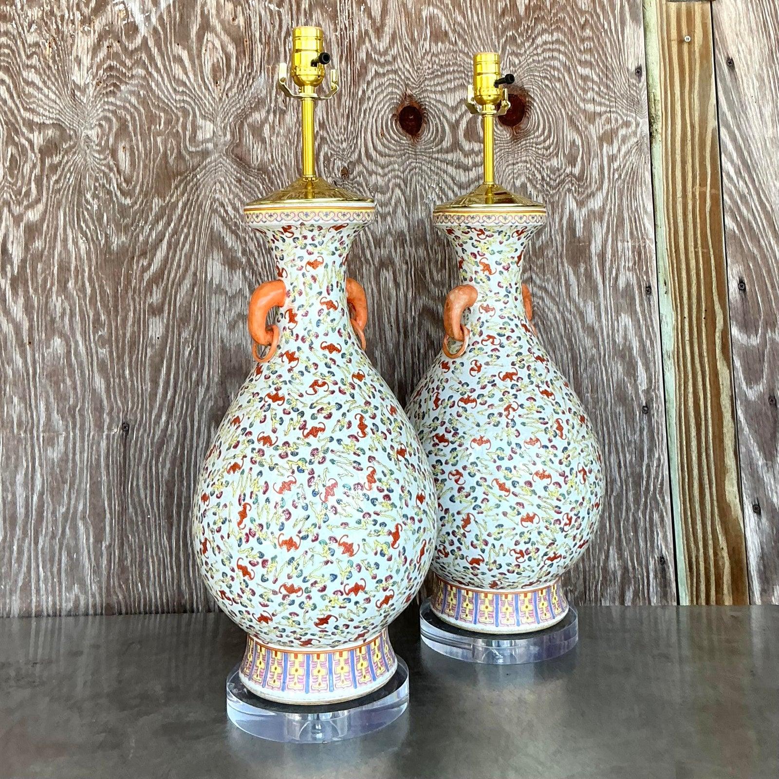 Illuminez votre espace avec le charme exquis de cette paire de lampes vintage, mêlant magnifiquement l'élégance Regency à l'art de la Chinoiserie. Chaque lampe présente un gracieux corps de vase en céramique orné d'un motif floral dense et captivant