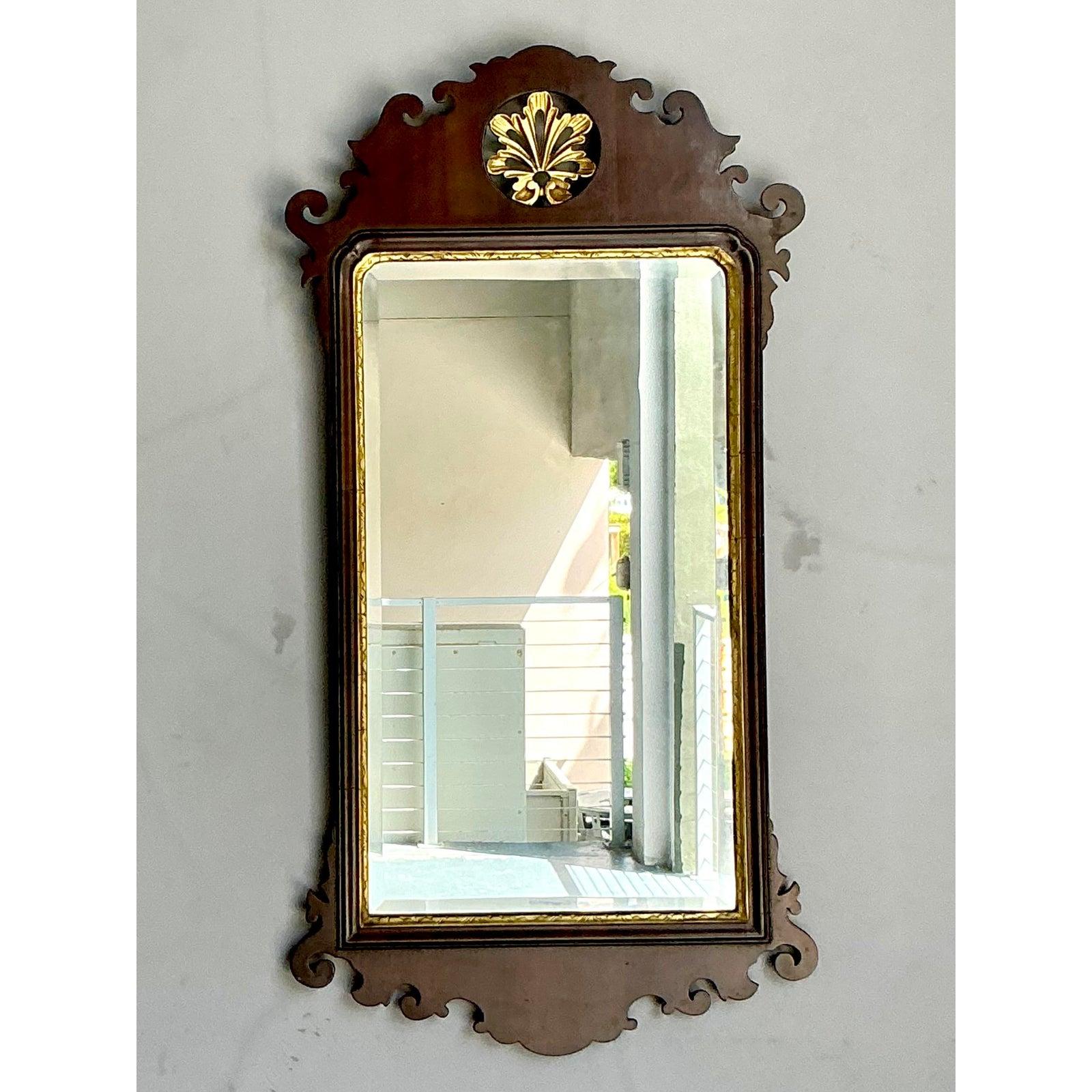 Aggiungi un tocco di eleganza architettonica senza tempo alle tue pareti con questo splendido specchio vintage in stile Chippendale. Realizzato con maestria in un ricco legno di mogano, questo pezzo è definito dalla sua graziosa silhouette a volute,