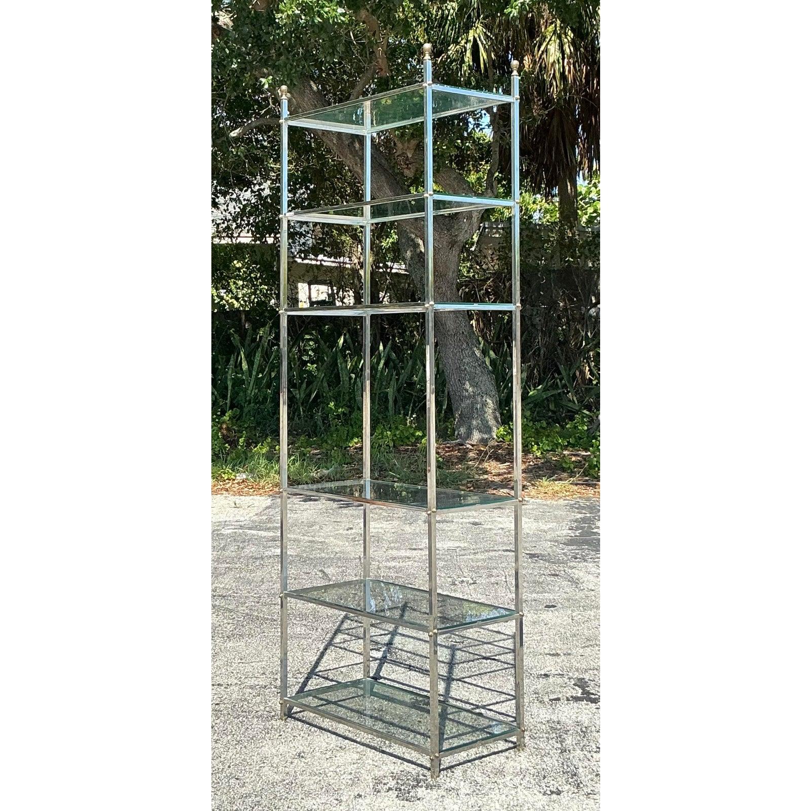 D'une élégance intemporelle et d'un glamour sophistiqué, cette étagère vintage est fabriquée de main de maître dans le style emblématique de la Maison Jansen. Le cadre imposant, fabriqué en chrome poli, présente de minces montants en forme de