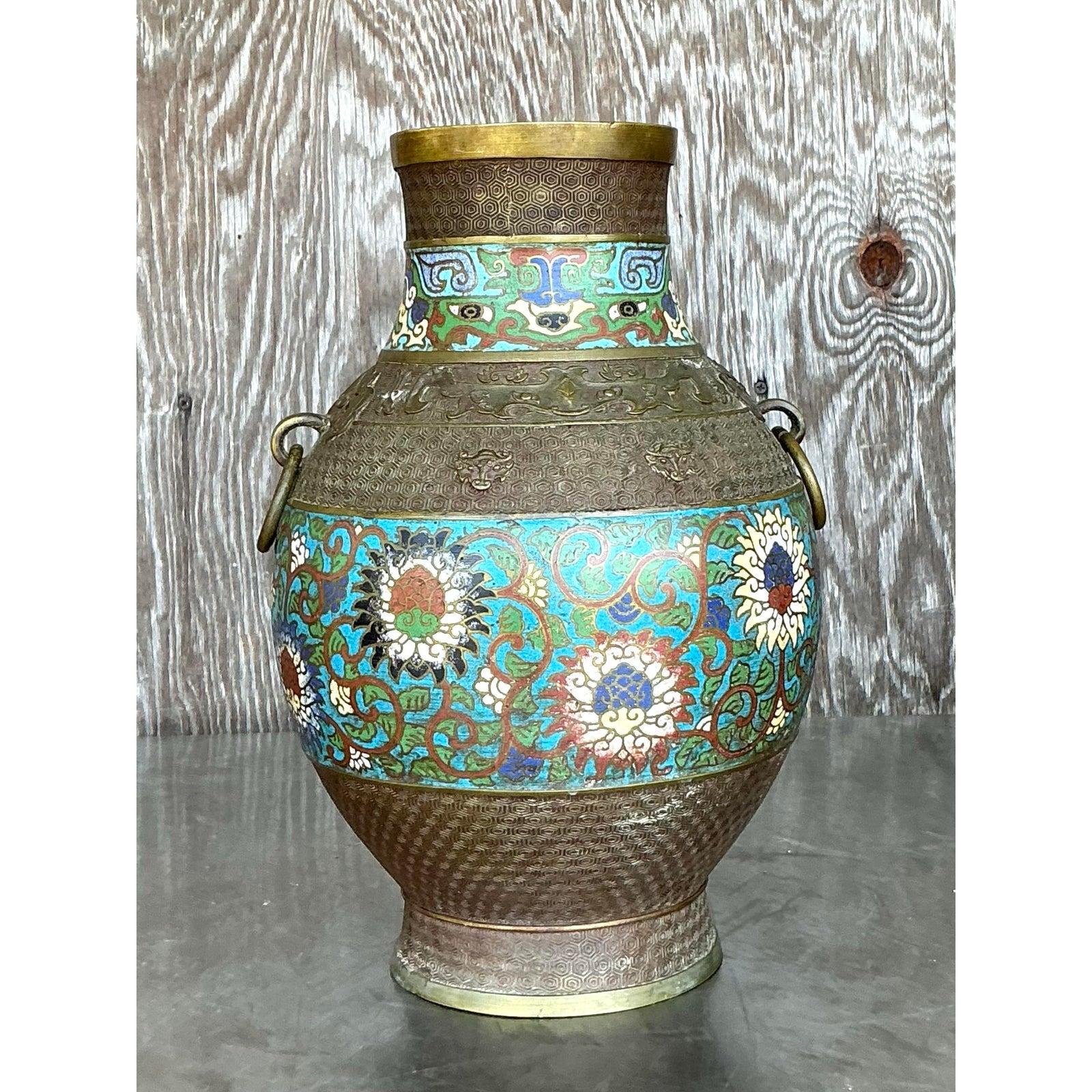 Celebra un'eleganza senza tempo con questo straordinario vaso Cloisonné Vintage Regency, un capolavoro di colore, forma e intricata maestria artigianale. Adornato con motivi floreali tradizionali cinesi in ricche tonalità di turchese, cremisi e