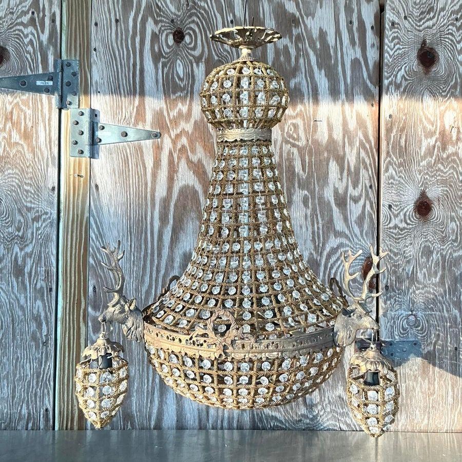Dieser Vintage-Kronleuchter aus Regency-Kristall verbindet Opulenz mit einem Hauch von rustikaler Eleganz. Er besticht durch aufwändige Kristalldetails und majestätische Hirsch-Akzente. Sein einzigartiges Design verleiht ihm einen luxuriösen, von