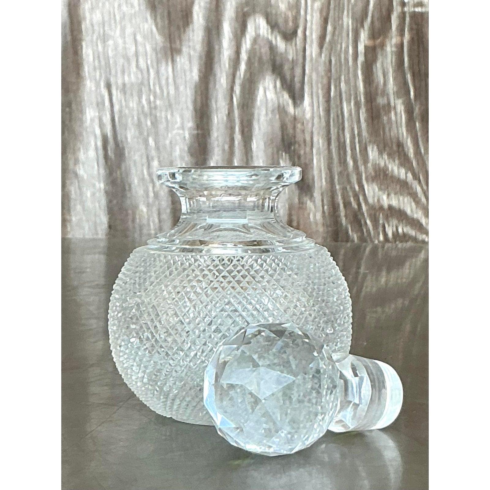 Elevate your vanity or bar cart with this exquisite vintage Regency cut crystal decanter. Showcasing a finely crosshatched texture on its rounded base and a brilliantly faceted stopper, this piece embodies timeless elegance and refined