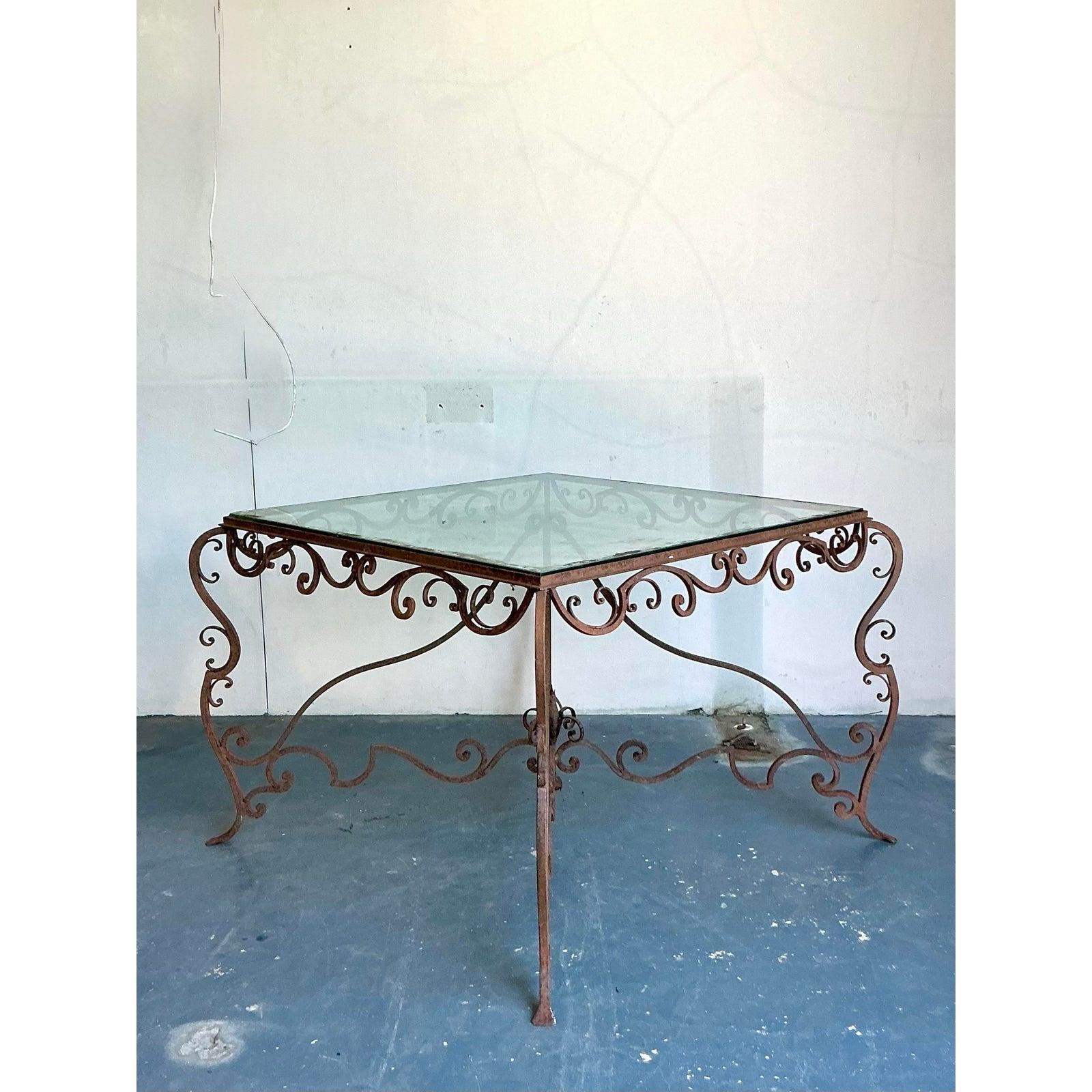 Commanding attention with its intricate artistry and enduring charm, this Vintage Regency Distressed Wrought Iron Scroll Dining Table offers a captivating blend of historical grandeur and versatile functionality. Hand-forged with masterful skill,
