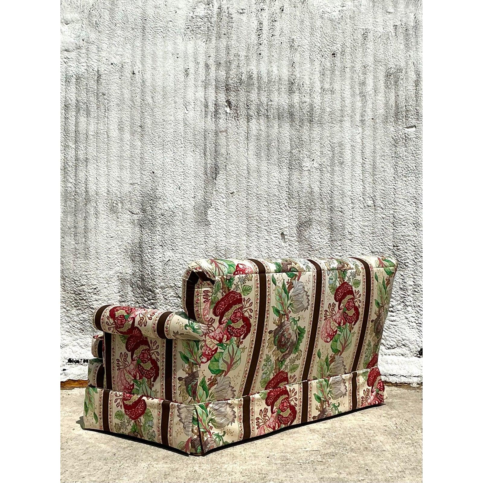 Infuse your space with timeless European flair through this vintage Regency-style loveseat, elegantly upholstered in Brunschwig & Fils' iconic “La Portugaise” fabric. Featuring a vibrant floral and shell motif set against vertical stripes, this