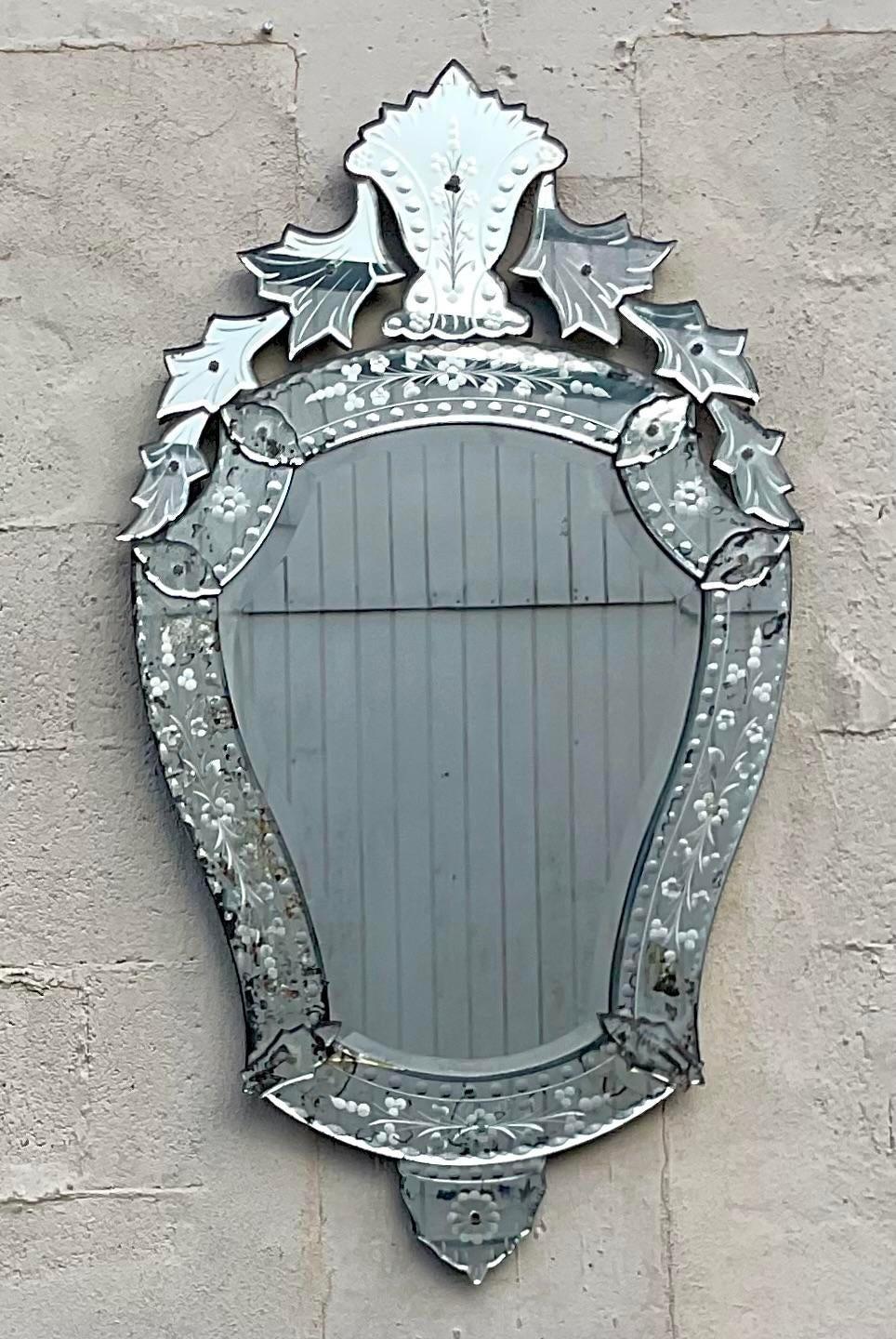 A fabulous vintage Regency wall mirror. A chic etched mirror in the classic Venetian style. An incredible all over patina from time with a distressed look to the glass. Perfect to add a flash of glamour to any space.