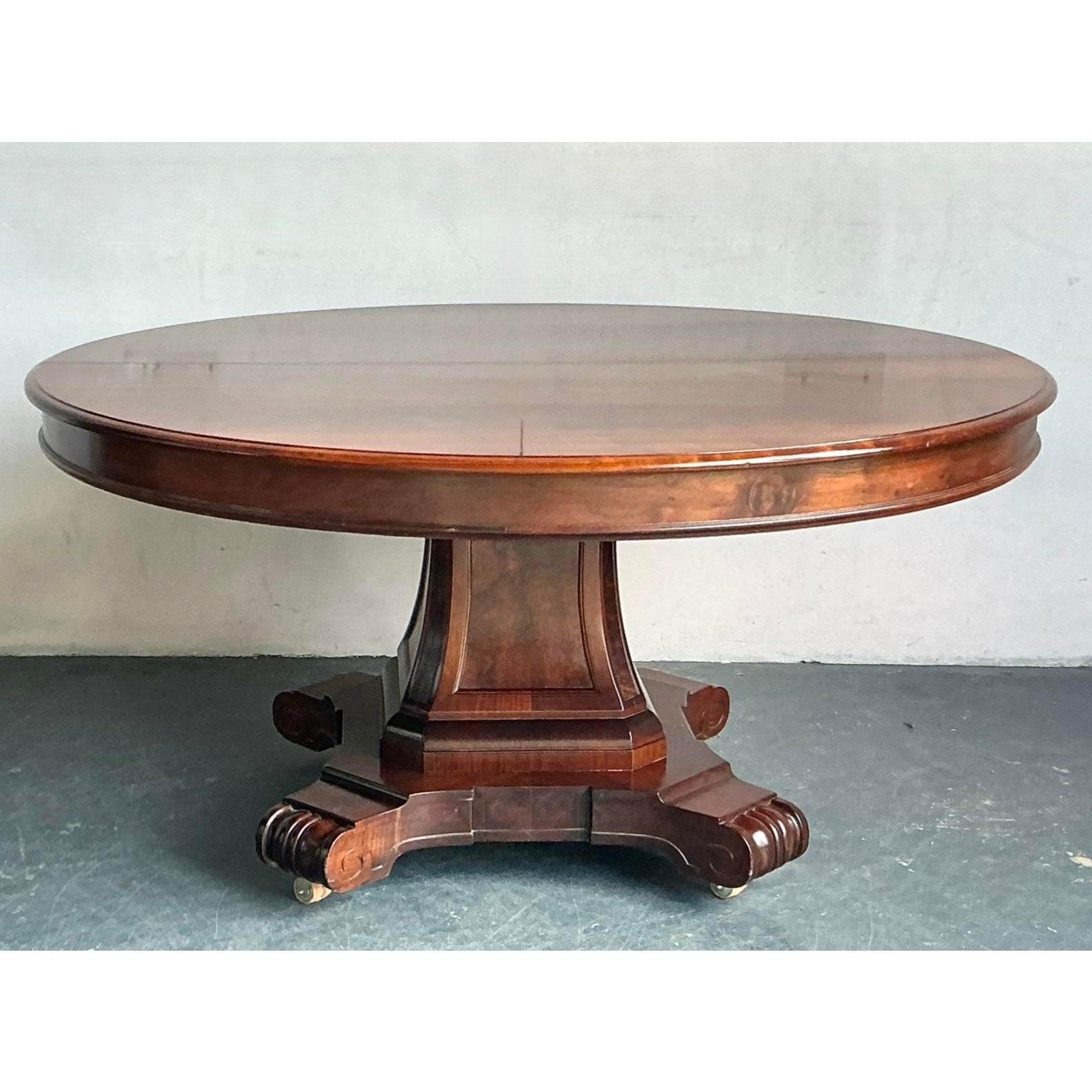 Elevate your dining experience with this magnificent Vintage Regency Extendable Mahogany Dining Table, a testament to enduring craftsmanship and timeless design. This piece exudes the refined elegance characteristic of the Regency era, featuring a