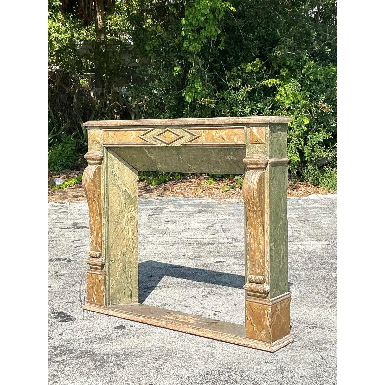 Ajoutez un caractère architectural audacieux à votre intérieur avec cet entourage de cheminée de style Regency vintage, doté d'une finition spectaculaire en faux marbre dans des tons vert terreux et or. Les sculptures ornées et les colonnes