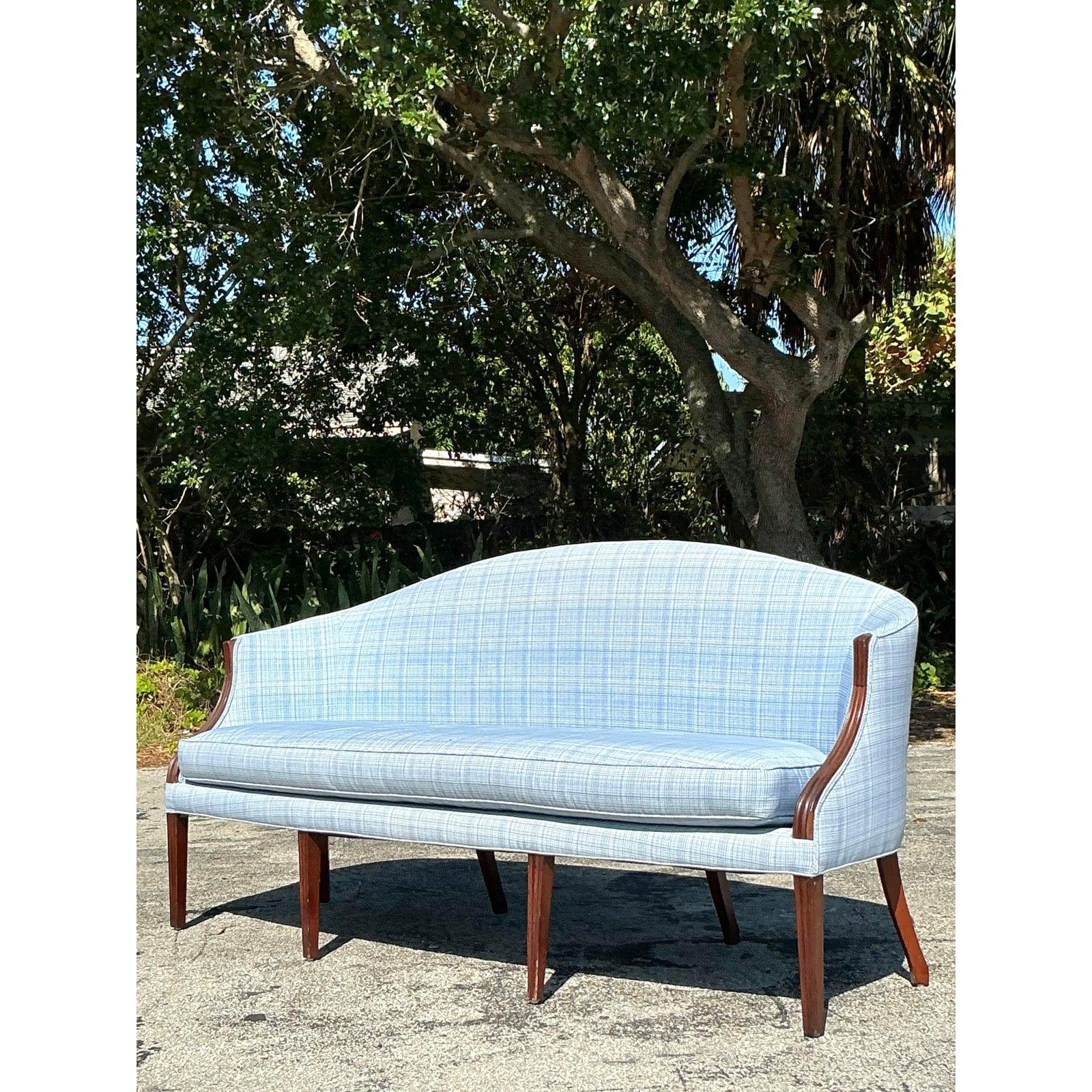 Sofisticato mix di eleganza classica e fascino sartoriale, questo divano vintage in stile Regency Feder presenta una struttura in mogano splendidamente curvata abbinata a una morbida imbottitura a quadri blu. Lo schienale pulito e arcuato, i