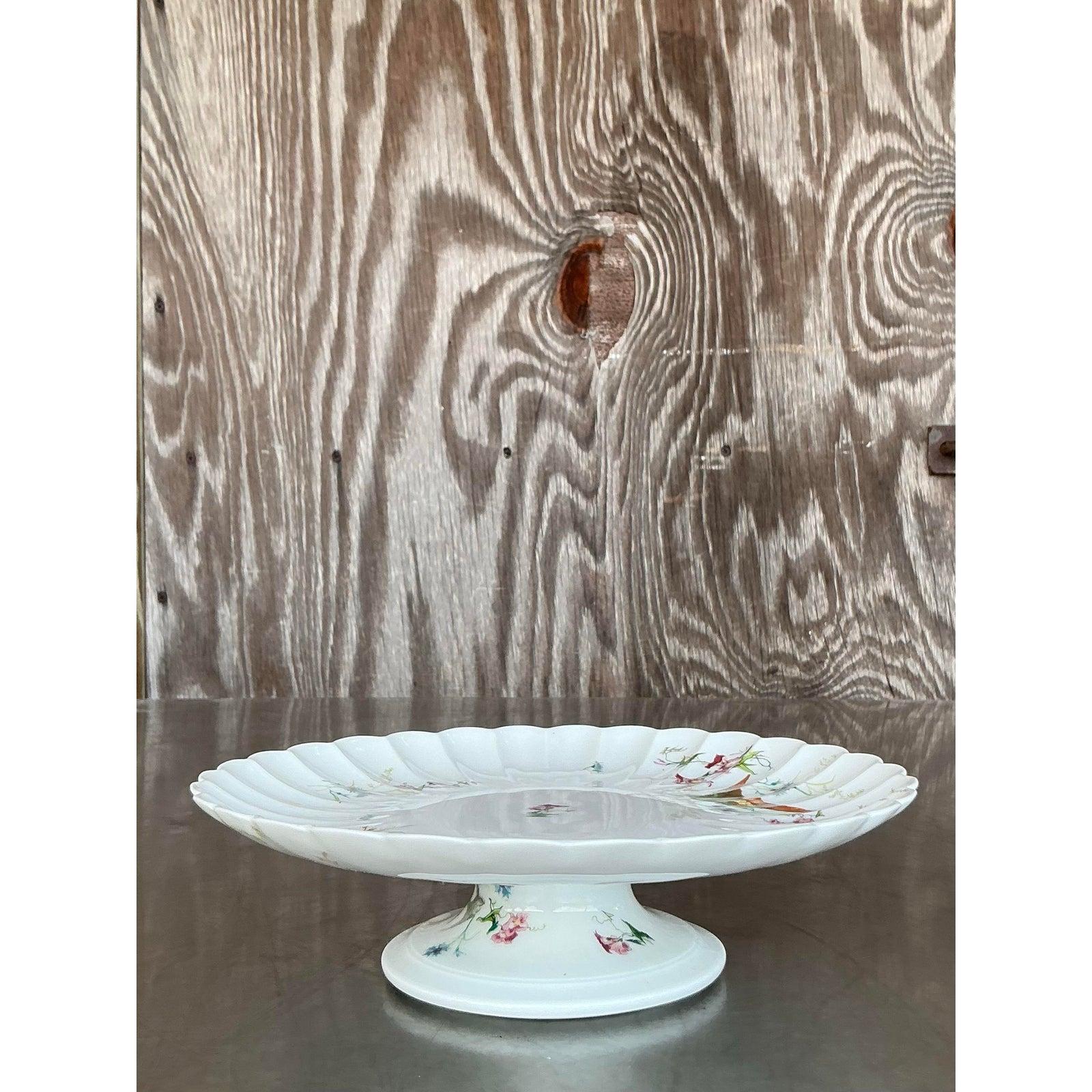Ajoutez un charme romantique à votre service avec cette exquise assiette à gâteau cannelée Vintage Regency Vermont Frères, délicatement ornée d'oiseaux et de fleurs peints à la main. Le bord légèrement festonné et le socle surélevé offrent une