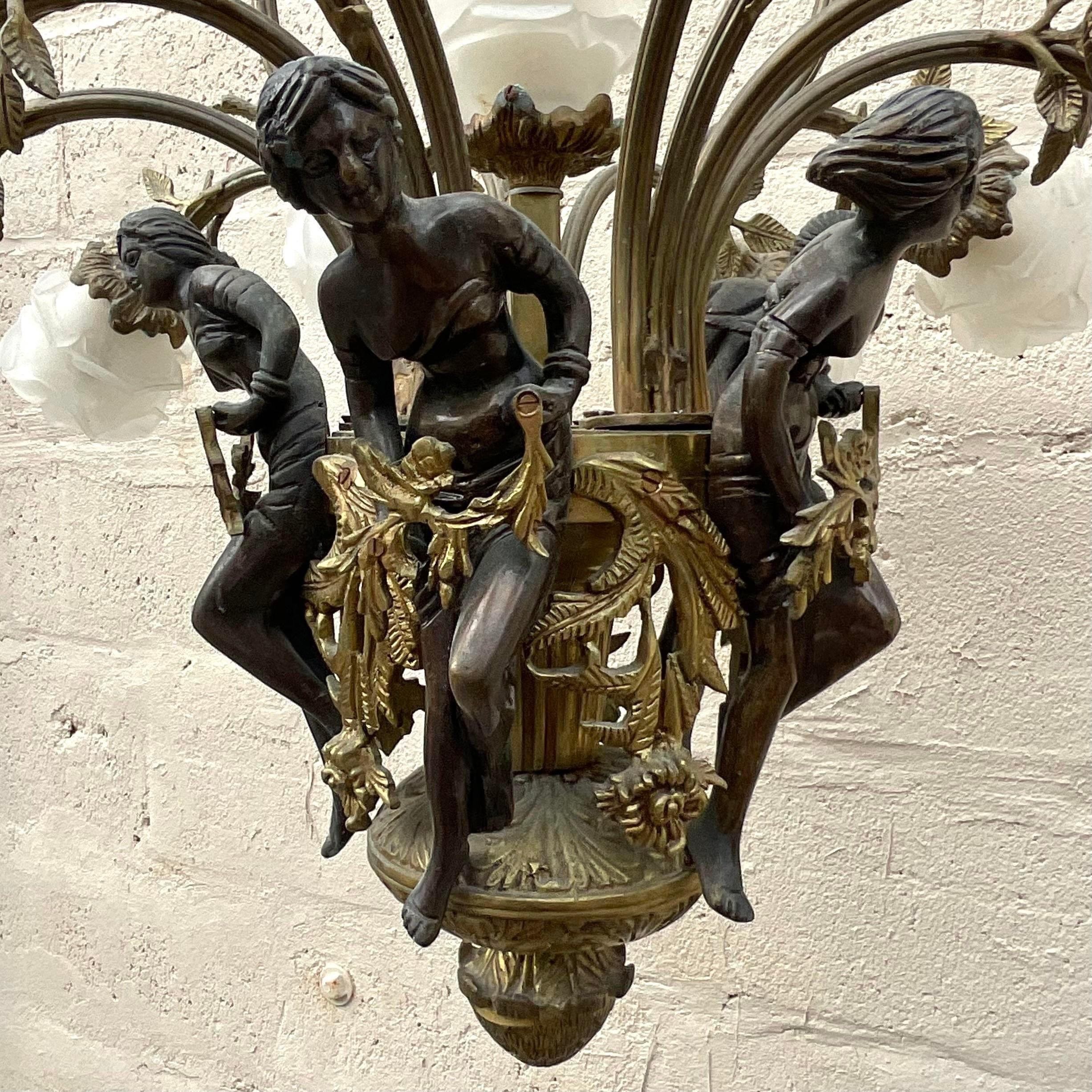 A stunning vintage Regency bronze chandelier. A chic Art Nouveau period piece with a ring of female figures and frosted rose glass shades. Acquired from a Palm Beach estate.