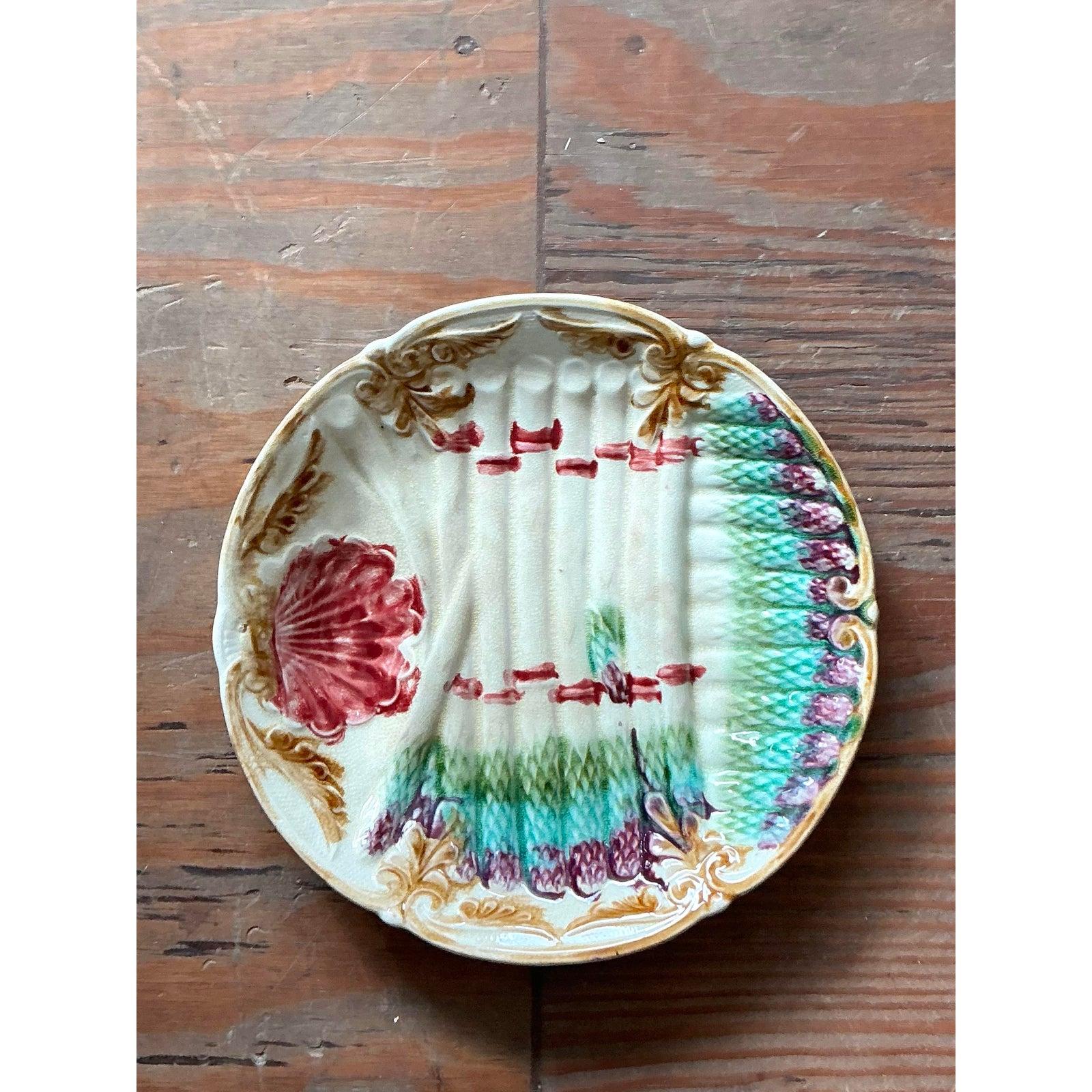 Dieser antike Majolikateller mit Spargel ist ein wahrer Klassiker der Barbotine-Tradition. Er ist ein entzückendes Stück französischer Keramikkunst, das sich für Sammler lohnt. Der Teller ist meisterhaft geformt, um ein Bündel Spargelstangen zu