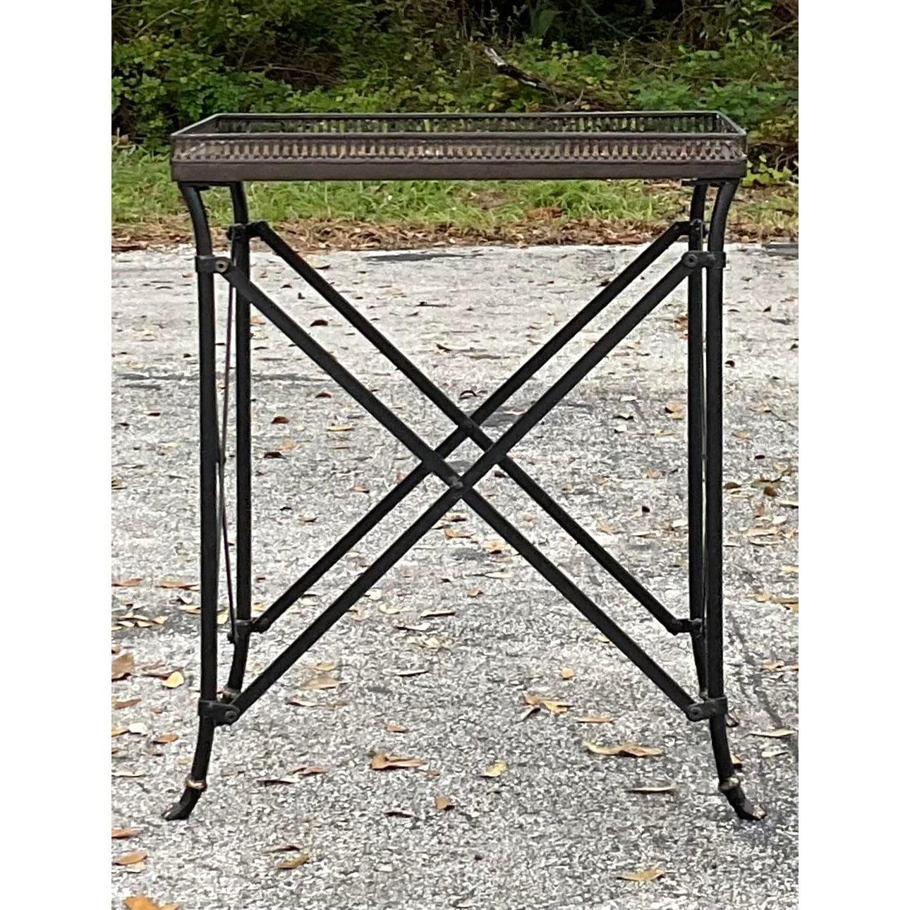 Introduce un toque de glamour sofisticado con esta mesa galería vintage Hollywood Regency. Esta elegante pieza de decoración tiene una bandeja de espejo extraíble, rodeada por una galería con finos detalles, sobre una elegante base en forma de X. La