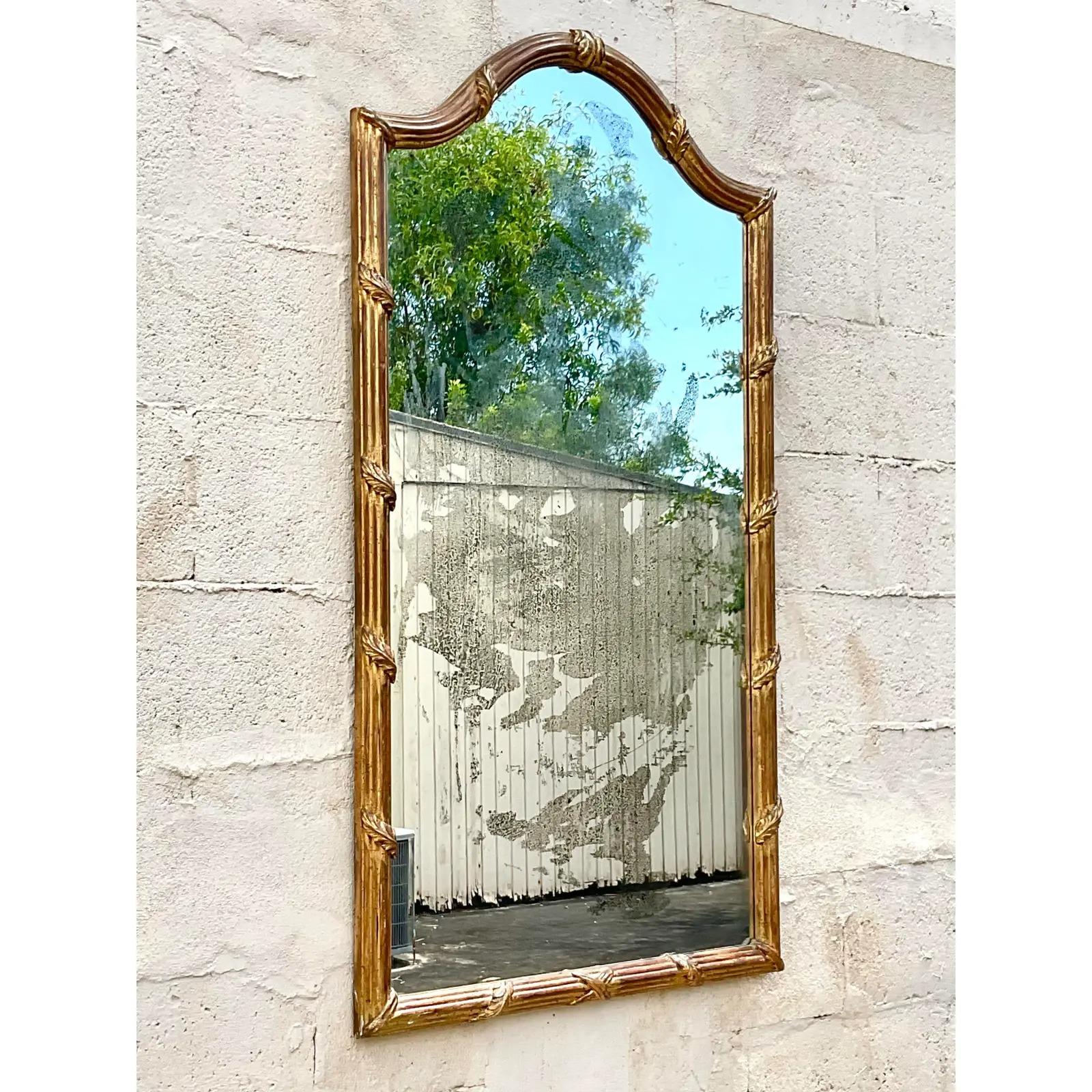 Magnifique miroir mural doré vintage. Chic détail de laurier enveloppé sur un cadre arqué. L'incroyable miroir vieilli ajoute une touche spectaculaire. Acquis d'une propriété de Palm Beach.