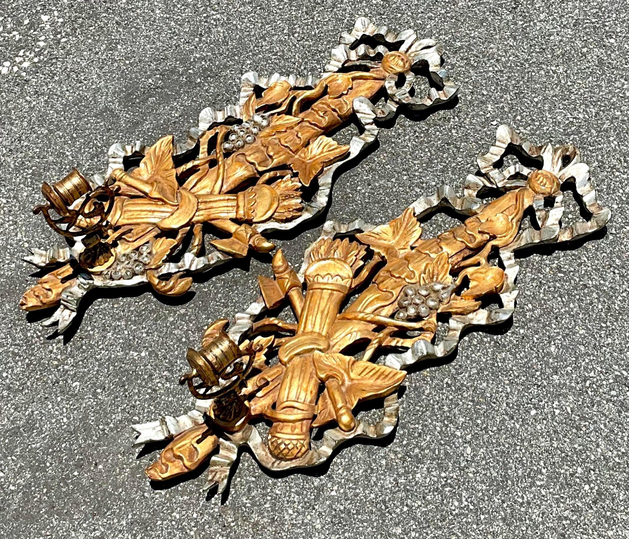 Cette paire d'appliques à bougie en bois sculpté et doré de style Vintage By est idéale pour embellir votre intérieur. Grâce à leur fabrication artisanale et à leur luxueuse finition dorée, ces appliques reflètent l'élégance et l'opulence du style