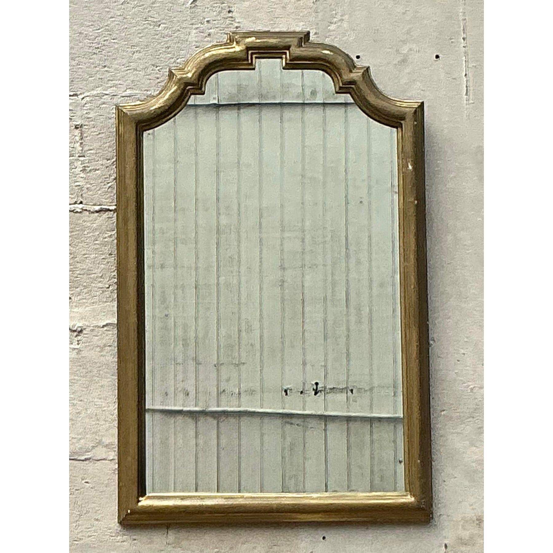 Cet exquis miroir vintage de style Regency présente un élégant cadre d'inspiration Chippendale avec une finition dorée saisissante. La silhouette magnifiquement incurvée et les détails ornés évoquent la sophistication classique, ce qui en fait une