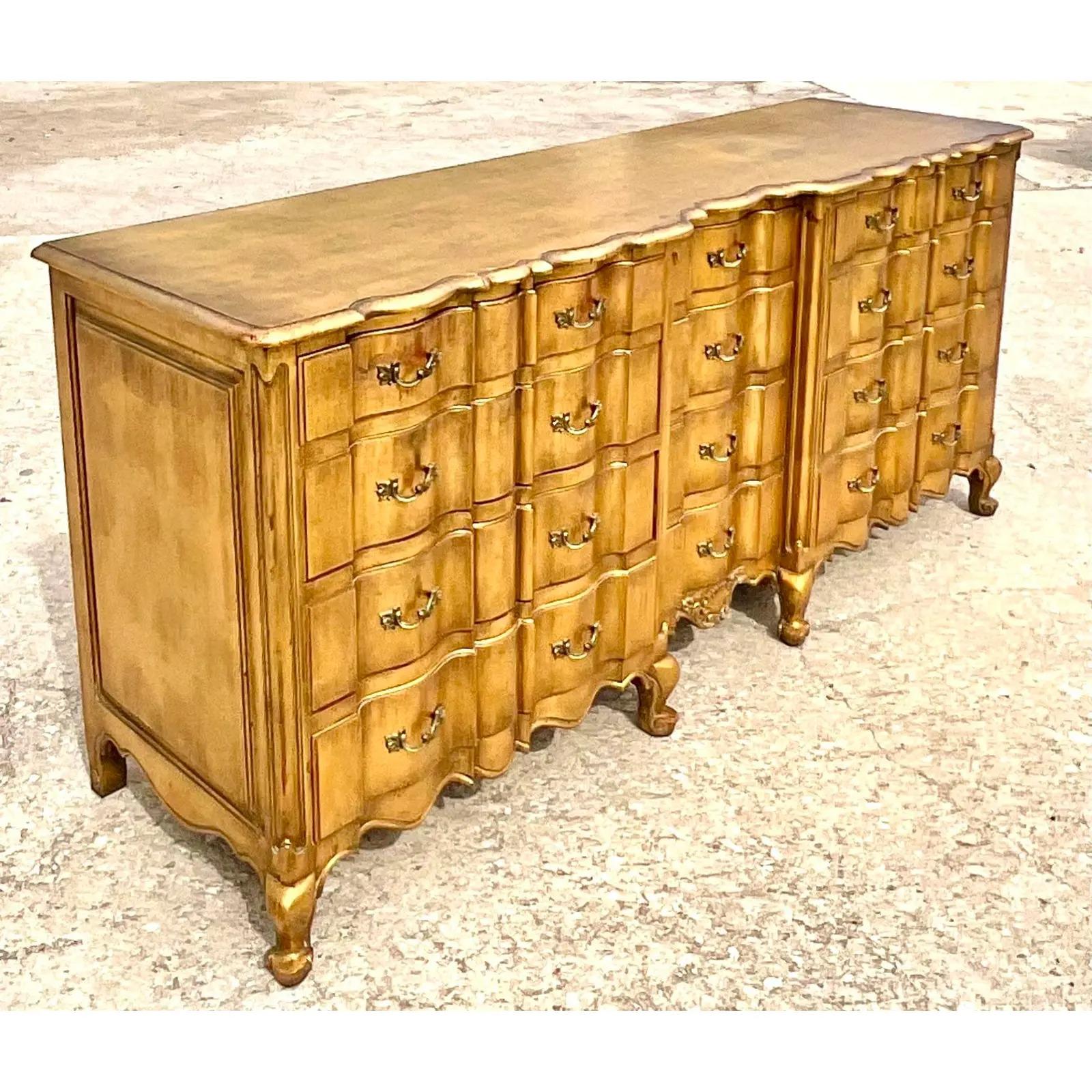 Fabulous vintage Regency dresser. A chic wave front design in a bright all over gilt finish. Sure to add a glass of drama to any space. Acquired from a Palm Beach estate.