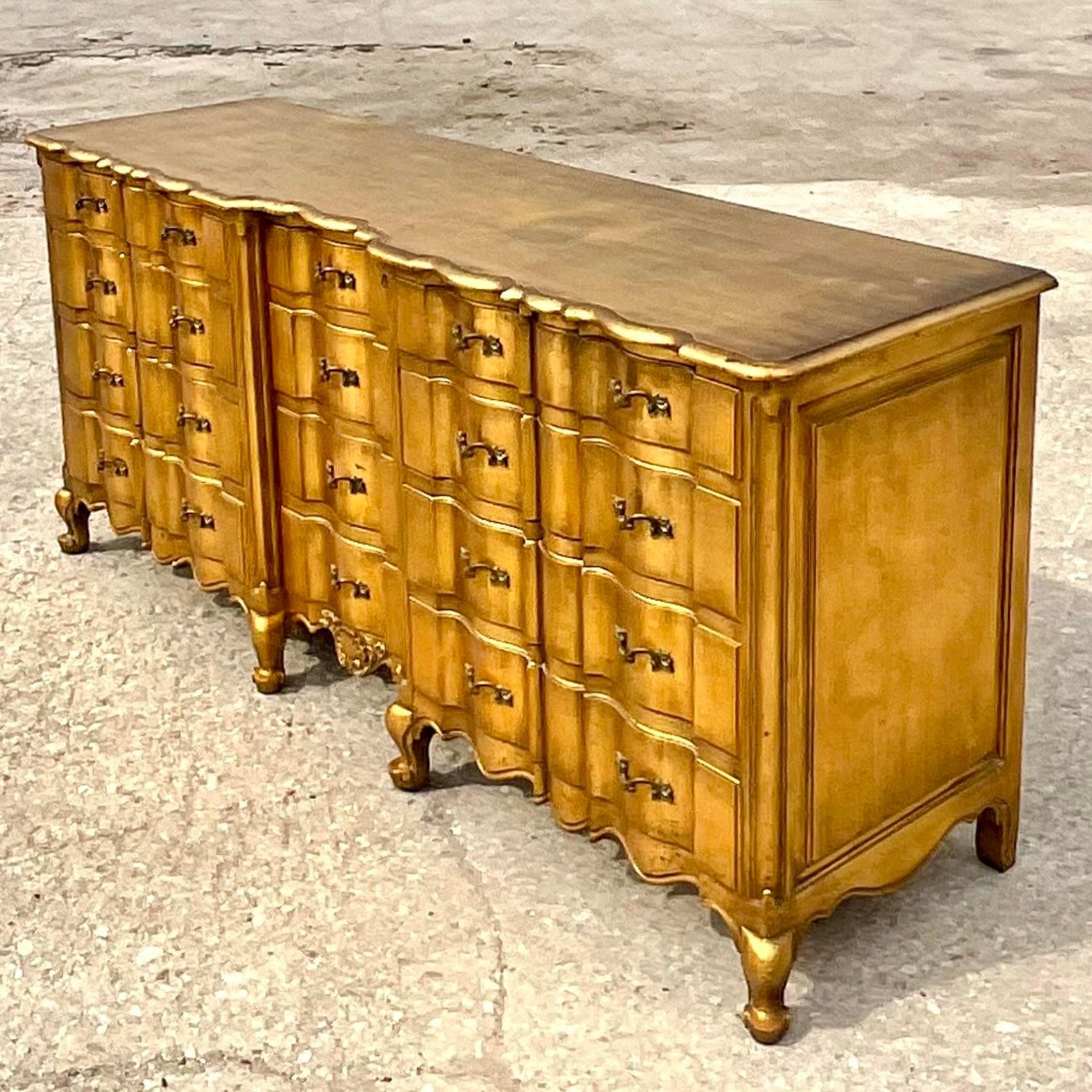 Fabulous vintage Regency dresser. A chic wave front design in a bright all over gilt finish. Sure to add a glass of drama to any space. Acquired from a Palm Beach estate.